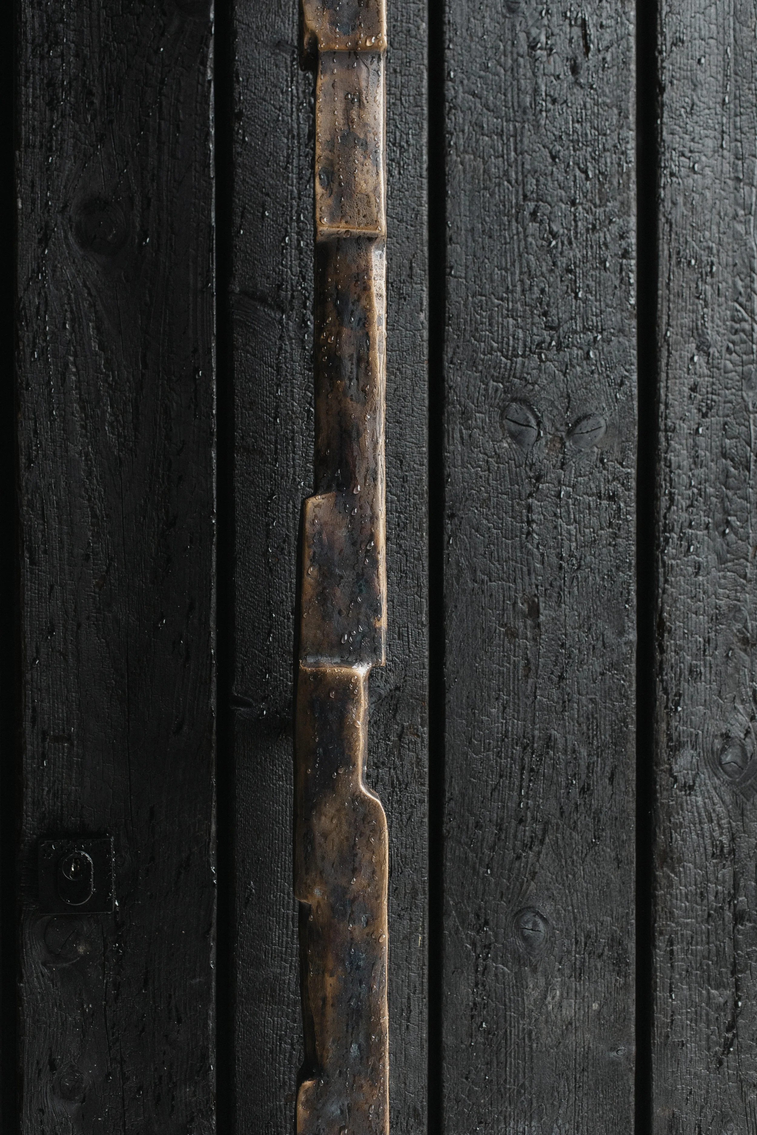 Close-up of a black painted wooden door with a bronzel handle.