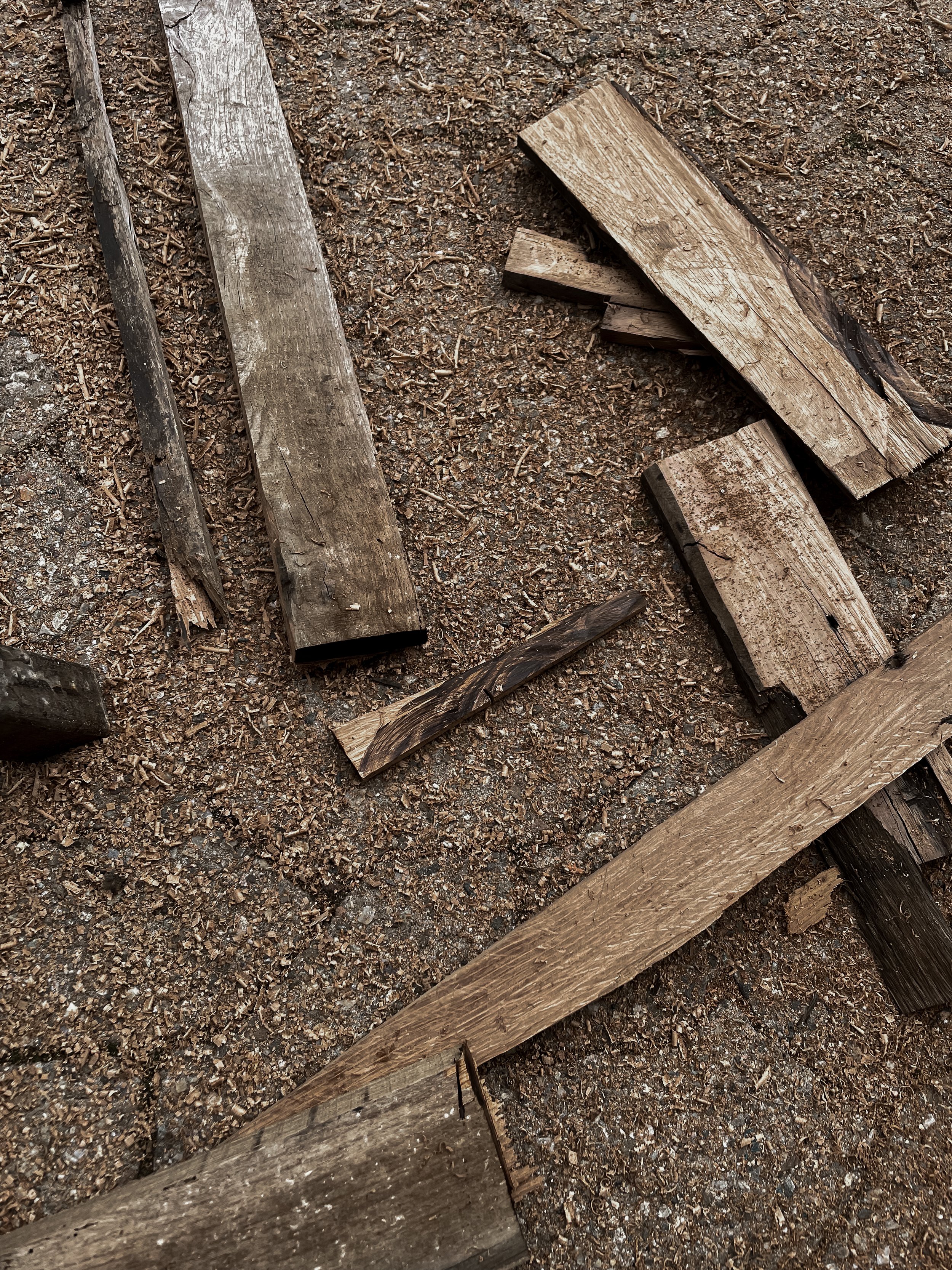 Various pieces of weathered and broken wooden planks and sticks scattered on dirt ground.