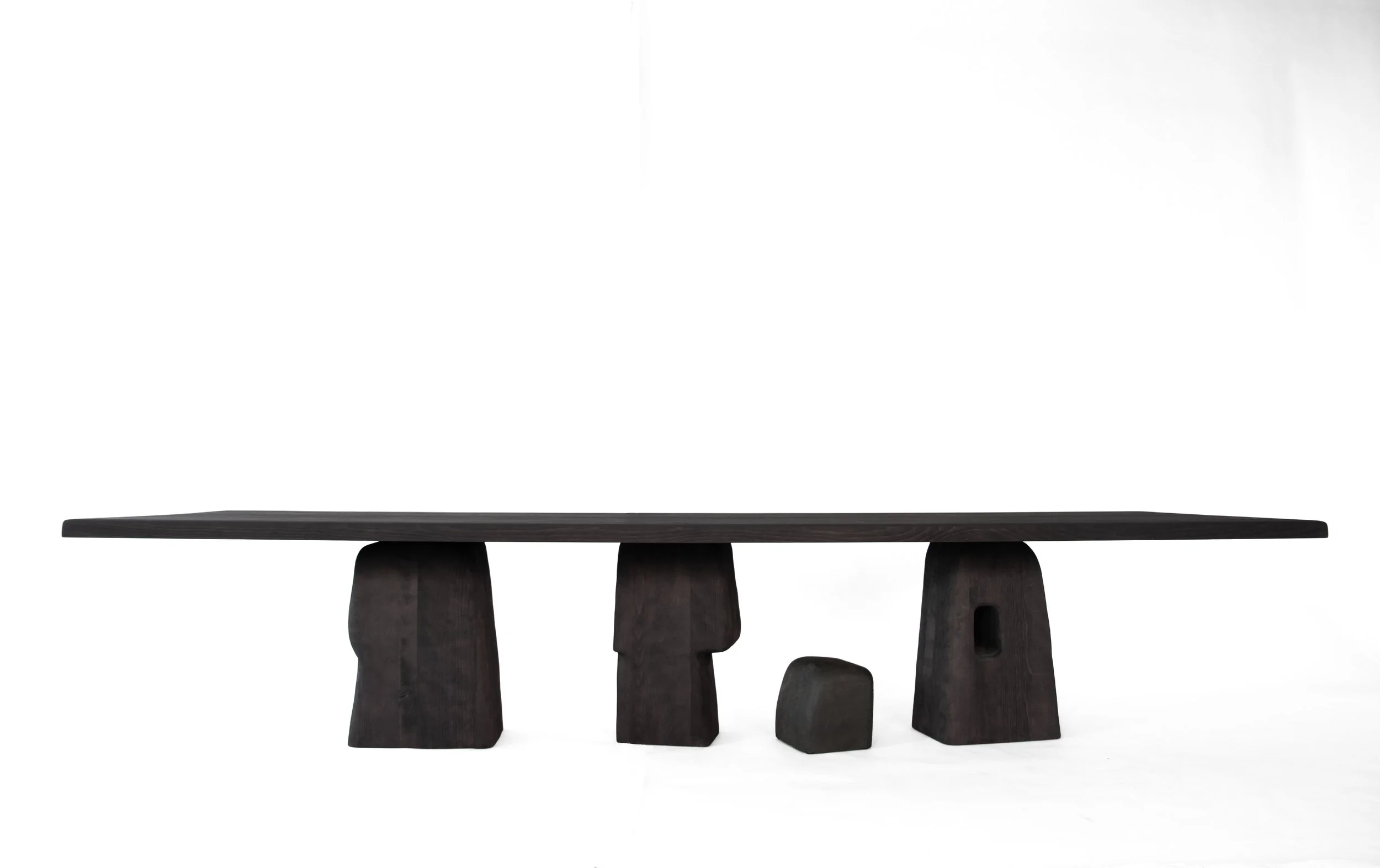 Modern black wooden table with abstract, irregular-shaped supports on a white background.