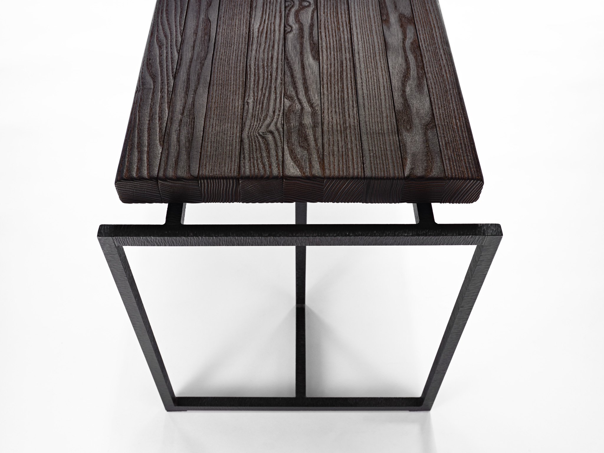 Close-up of a modern bench with a dark wooden top and black metal geometric base.