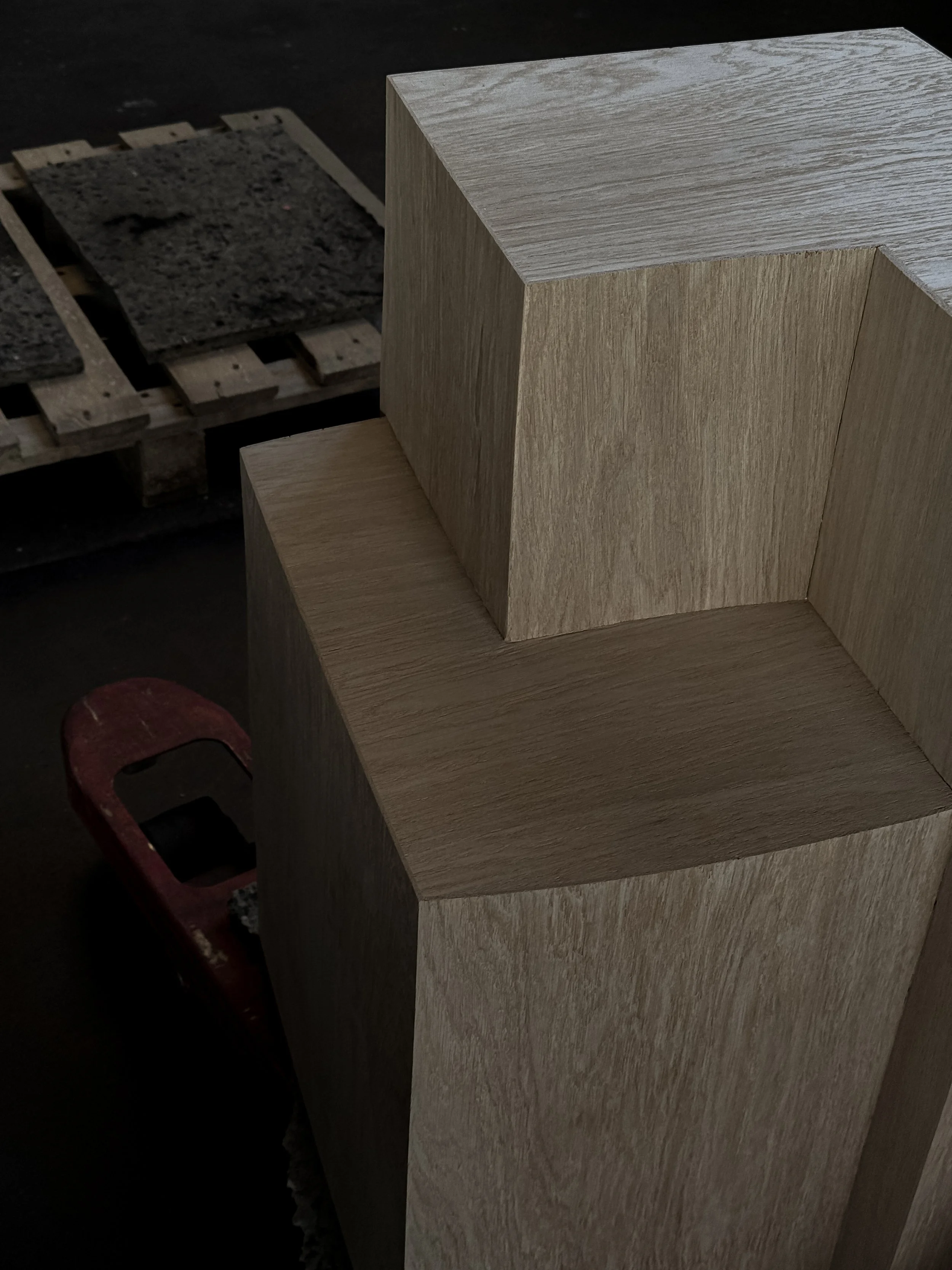 Close-up of two wooden blocks stacked on each other, with a palette and paint samples visible in the background.