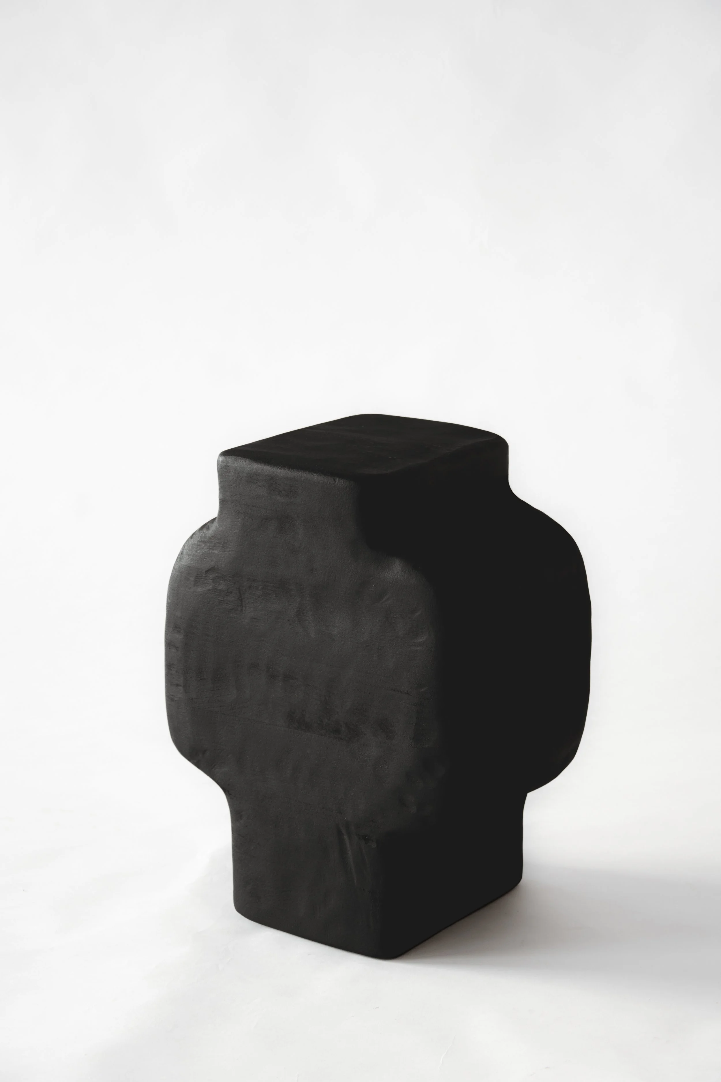Black abstract sculpture resembling a human head in profile, placed against a plain white background.