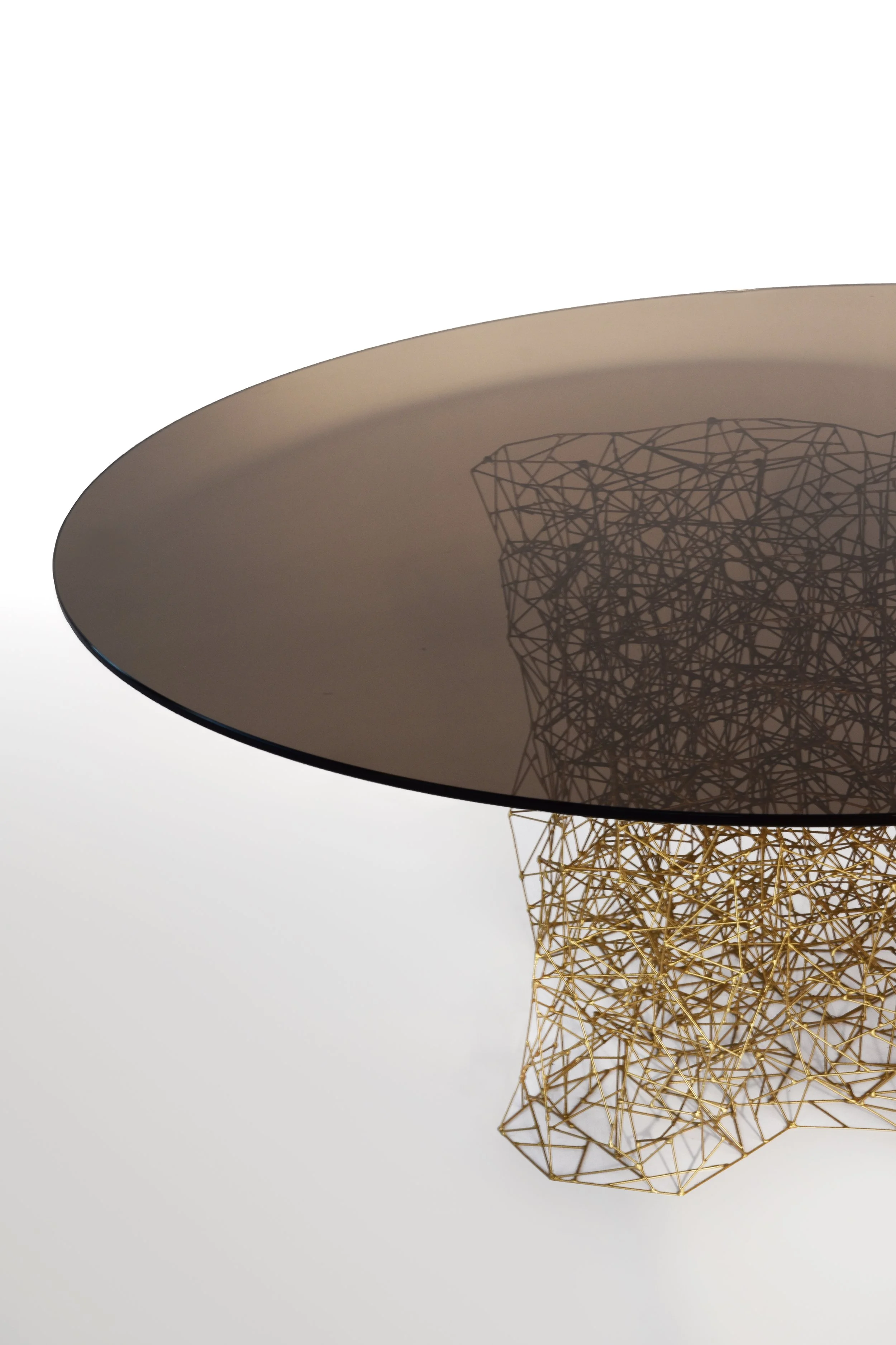 A modern, round table with a reflective, dark surface and a gold wireframe base.