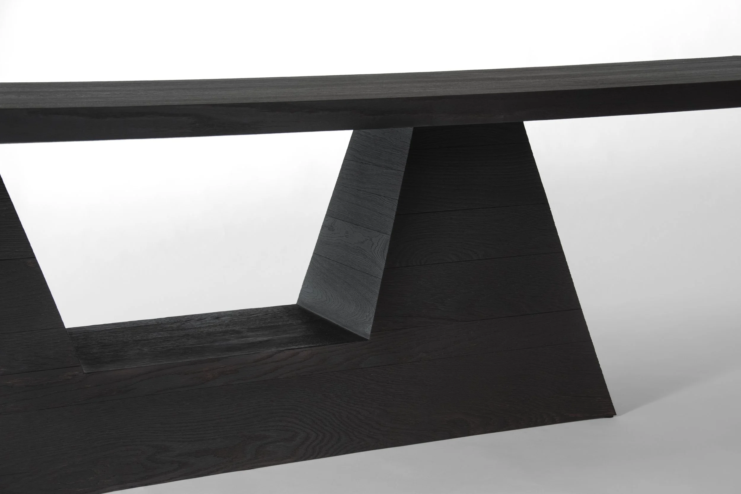 Close-up of a modern black wooden structure with a geometric design and open space, against a white background.