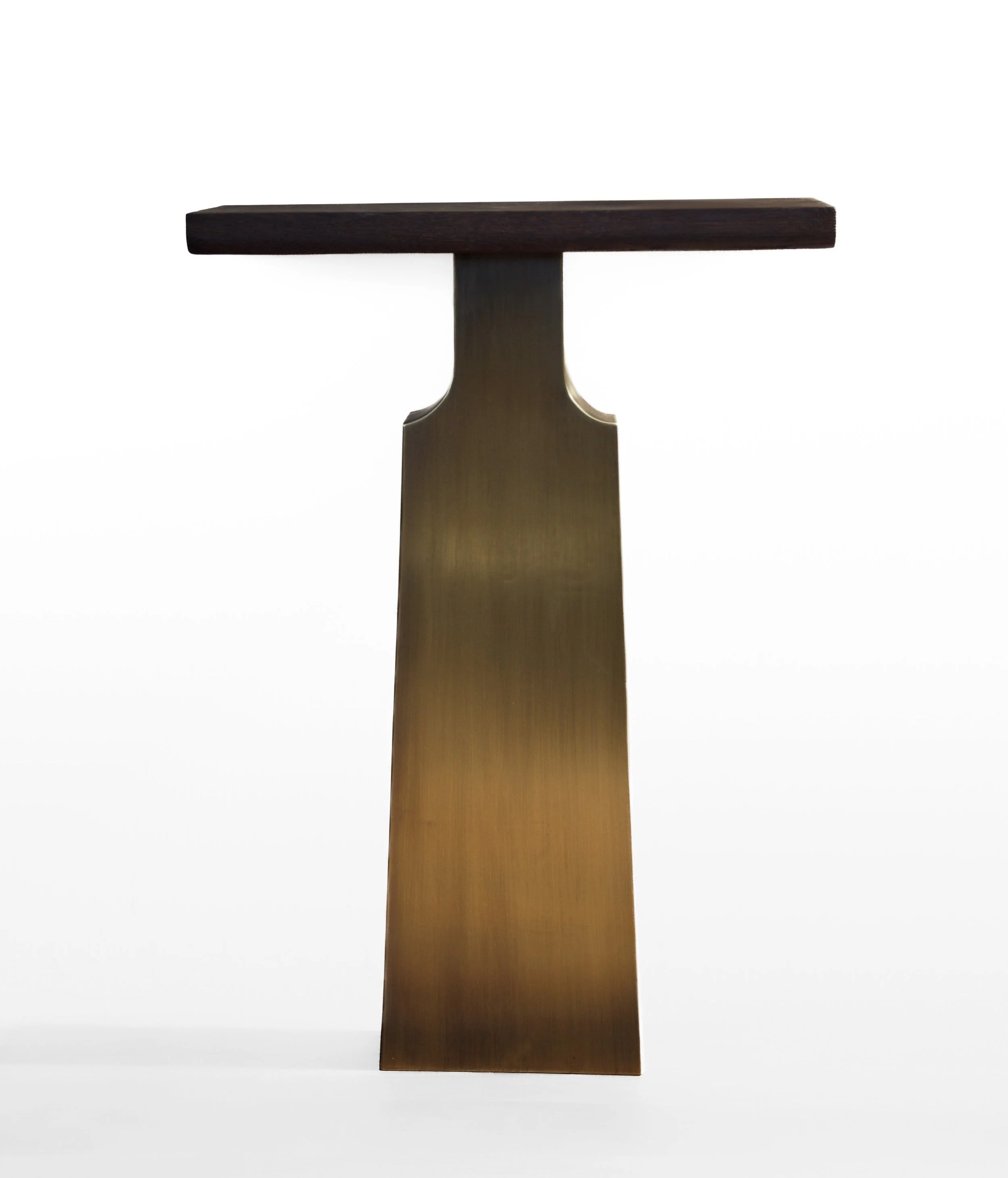 Sculpture composed of a dark wooden horizontal top and a gold-colored vertical base with curved sides, set against a plain white background.