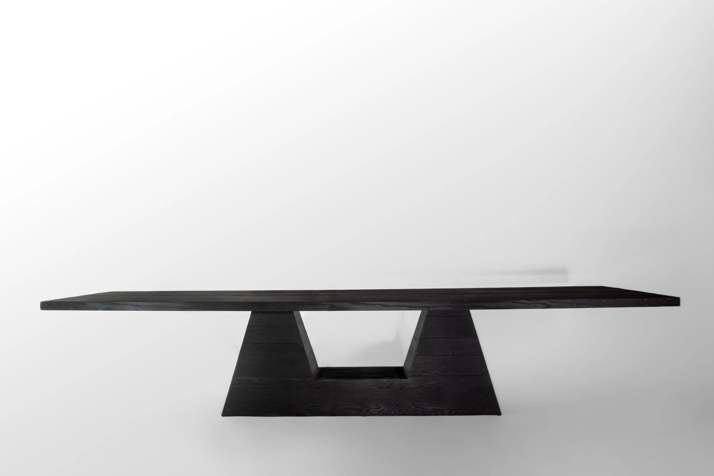 Black modern wooden table with geometric base on a plain white background.