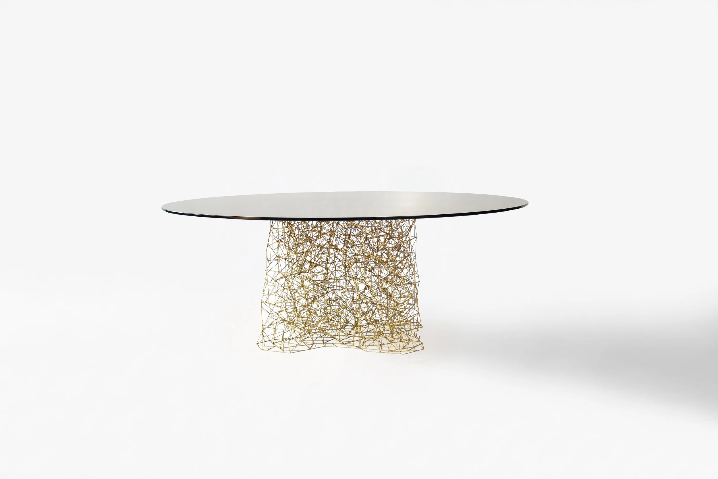 Modern table with a round black top and a base made of gold interconnected wireframe design.