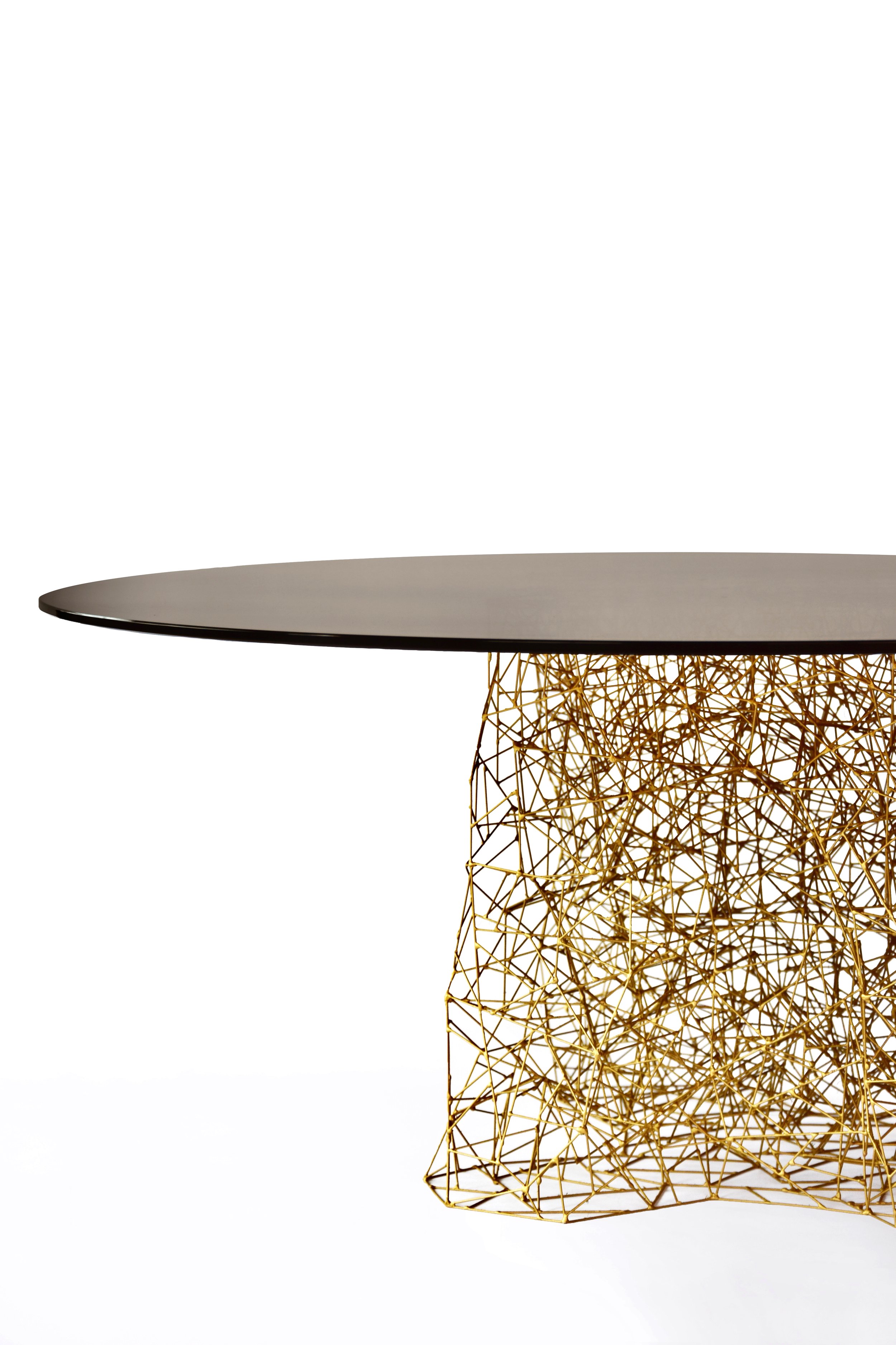 A modern table with a black tabletop and a gold wireframe geometric base.