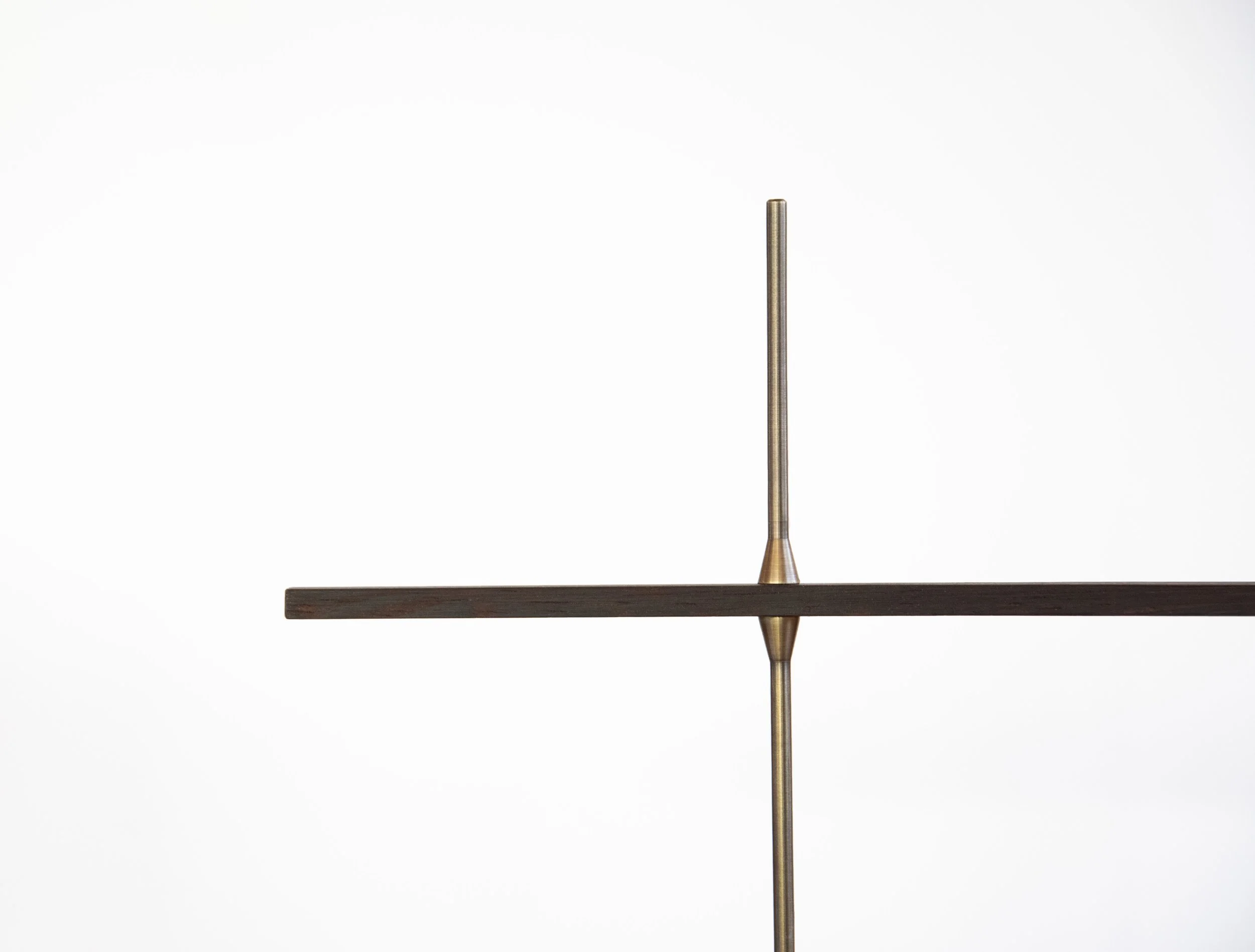 Minimalist abstract sculpture with a vertical metal rod intersecting a horizontal wooden plank against a plain white background.