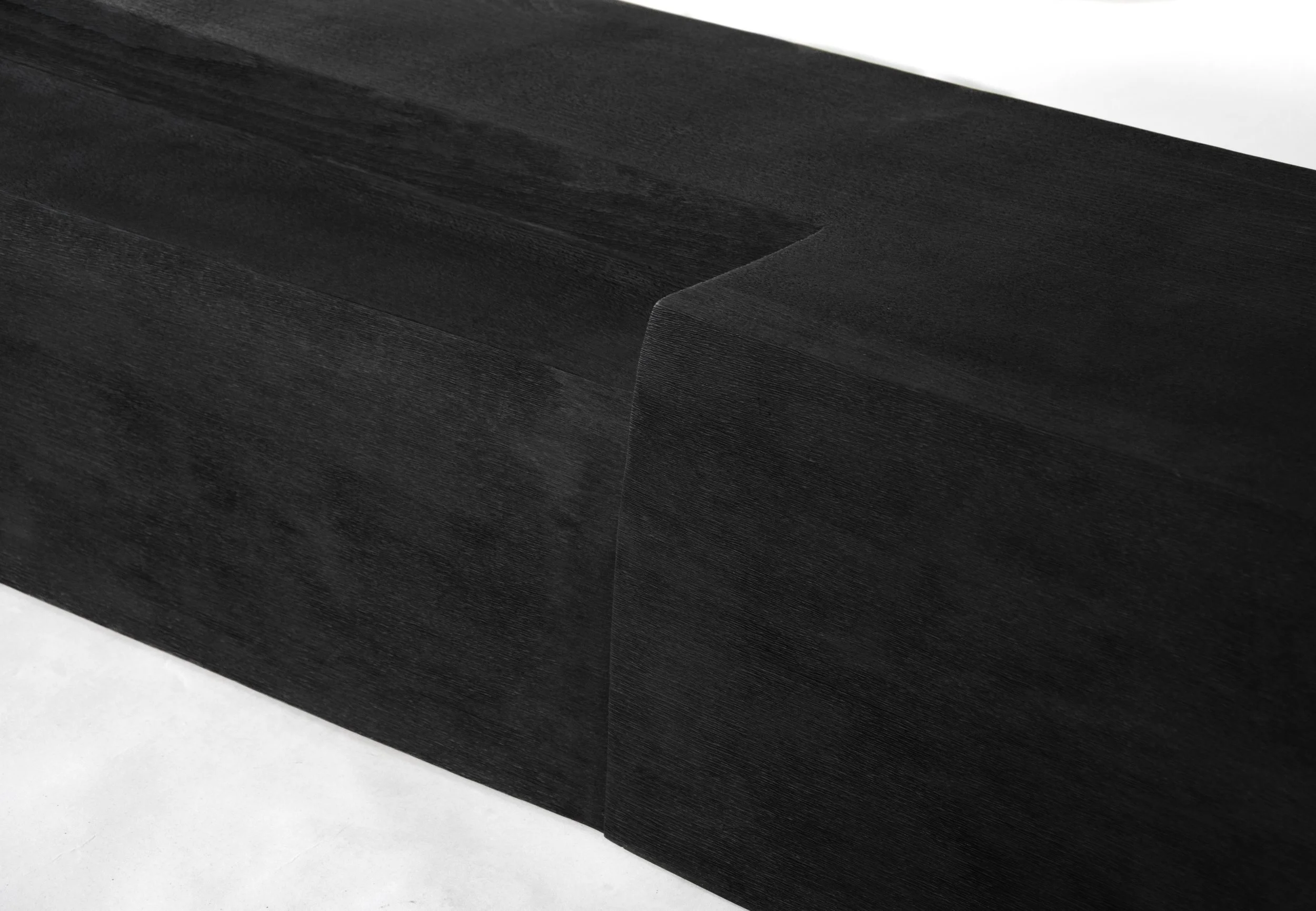 Close-up of a black wooden table corner with visible wood grain texture.