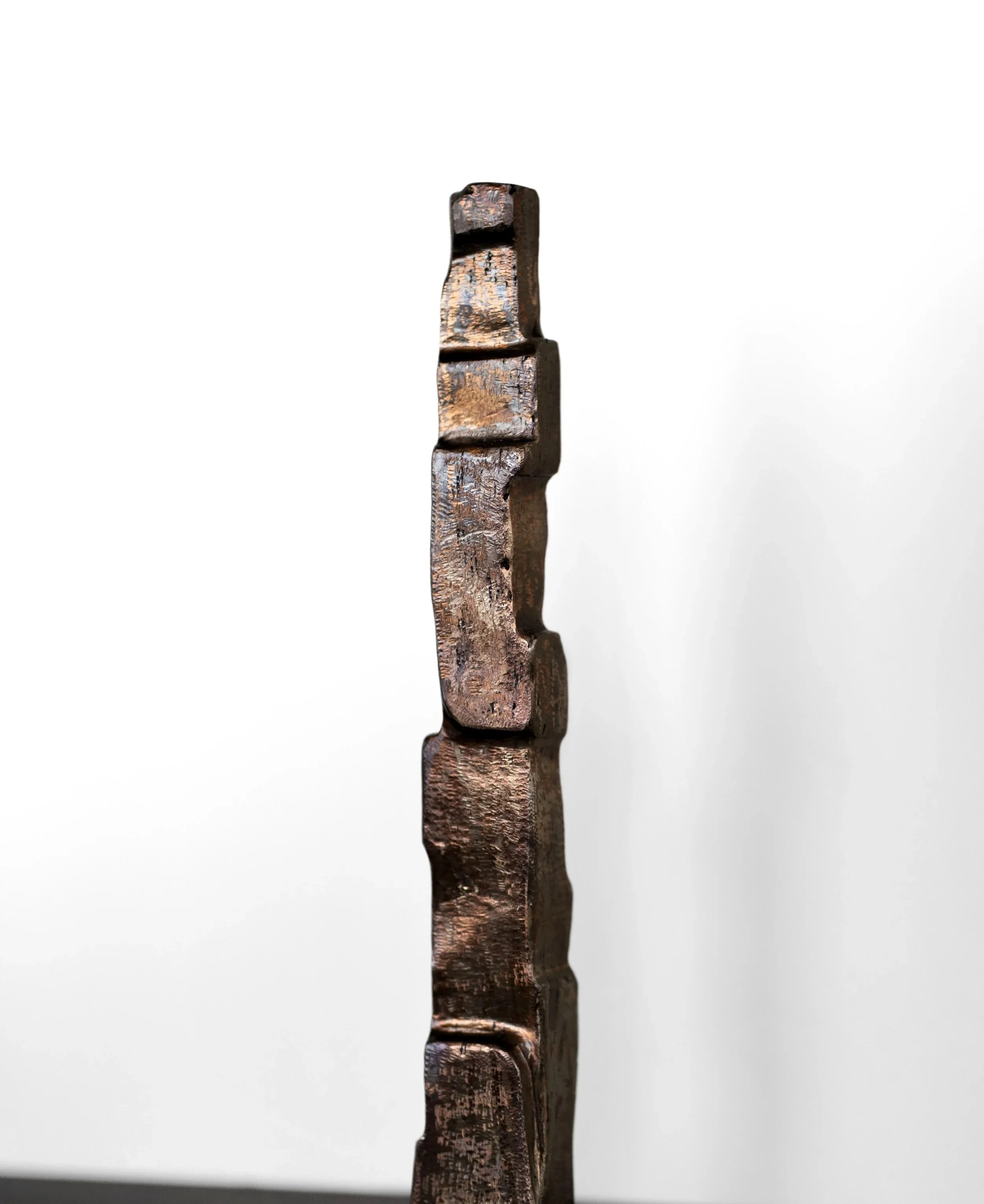 Close-up side view of a vertical stack of wooden blocks with a weathered, rustic appearance, against a plain white background.