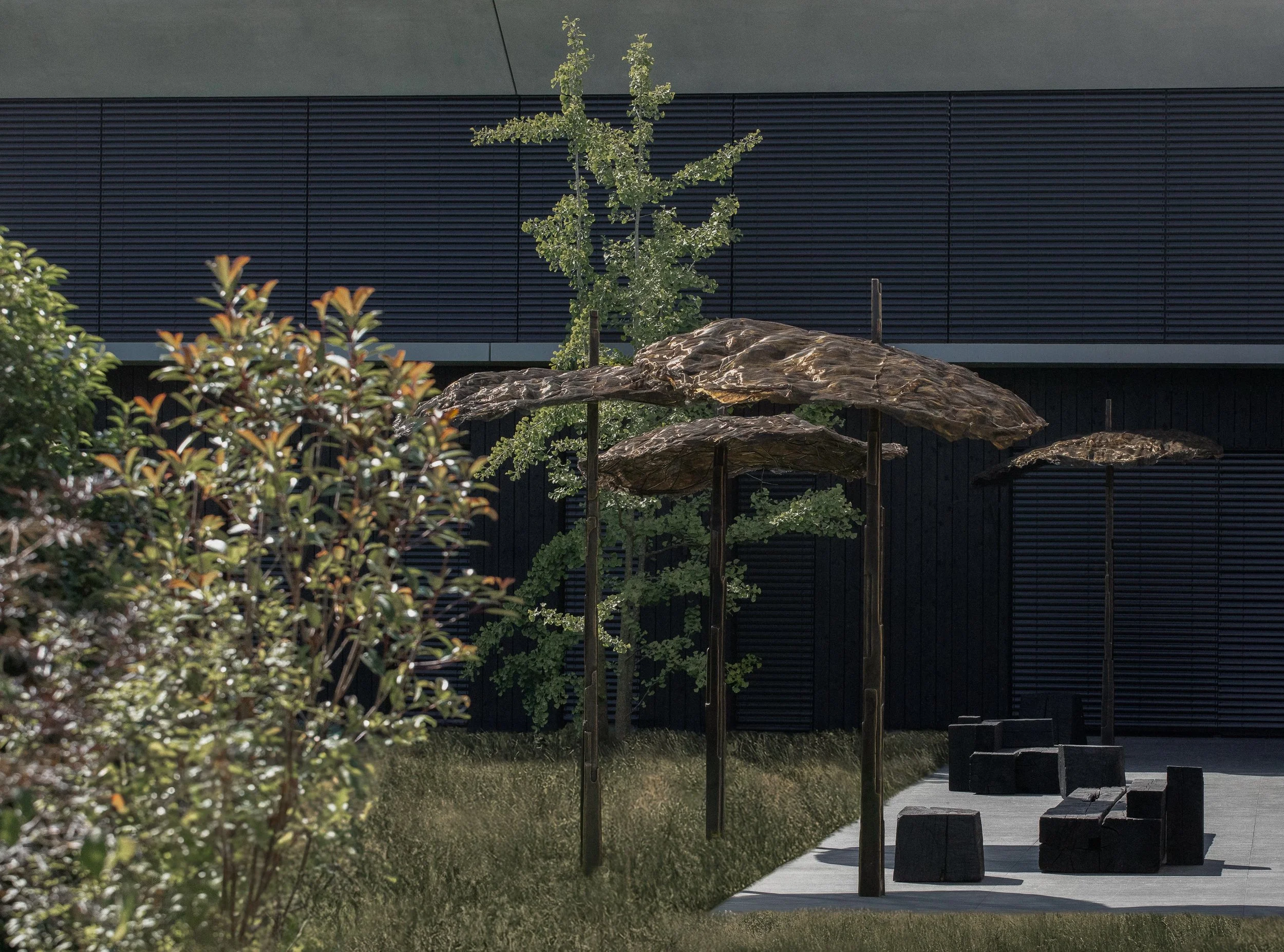 Outdoor seating area with dark wooden umbrellas, potted trees, and benches set on a gray tiled surface, with a black wall in the background.