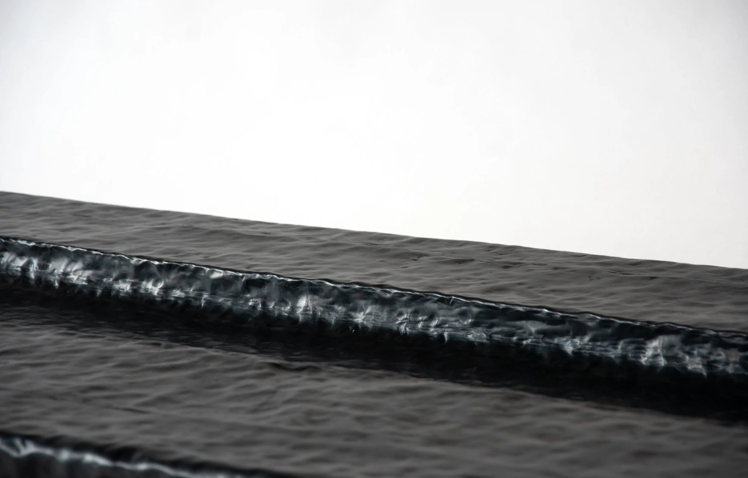 Close-up of a black sneaker with white soles resting on a dark textured surface.