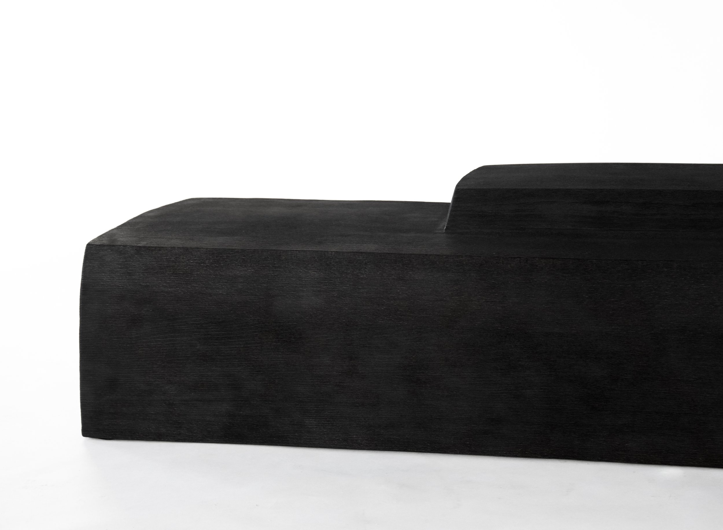 Close-up of a sleek black wooden object with a curved shape against a white background.