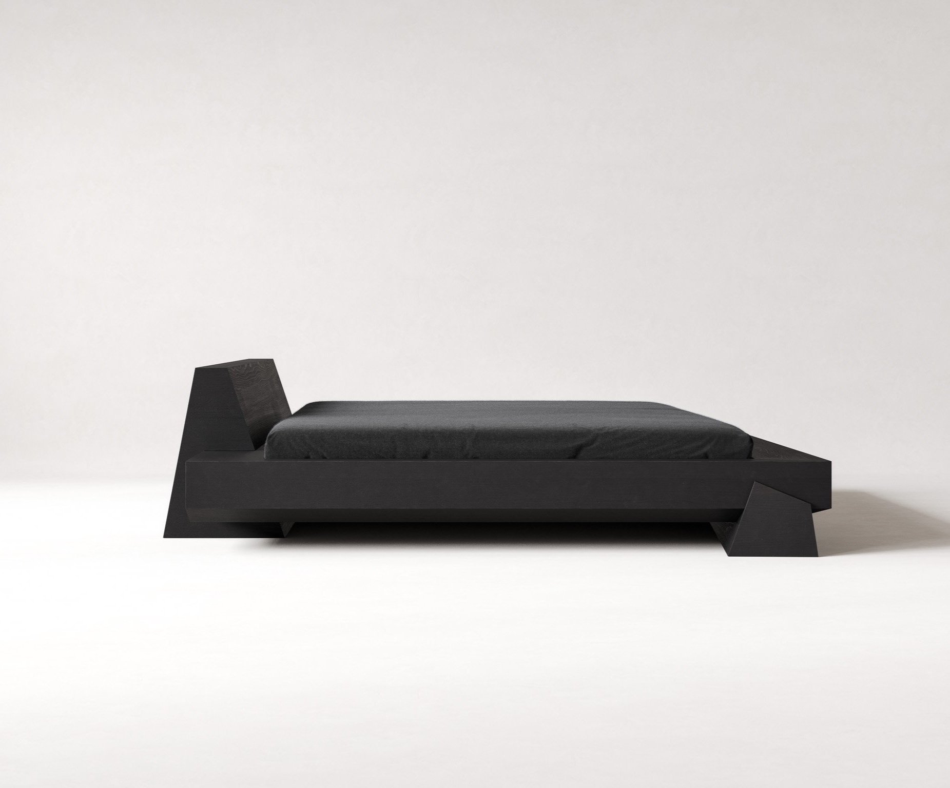 Minimalist black bed with a simple black mattress in a stark white room.