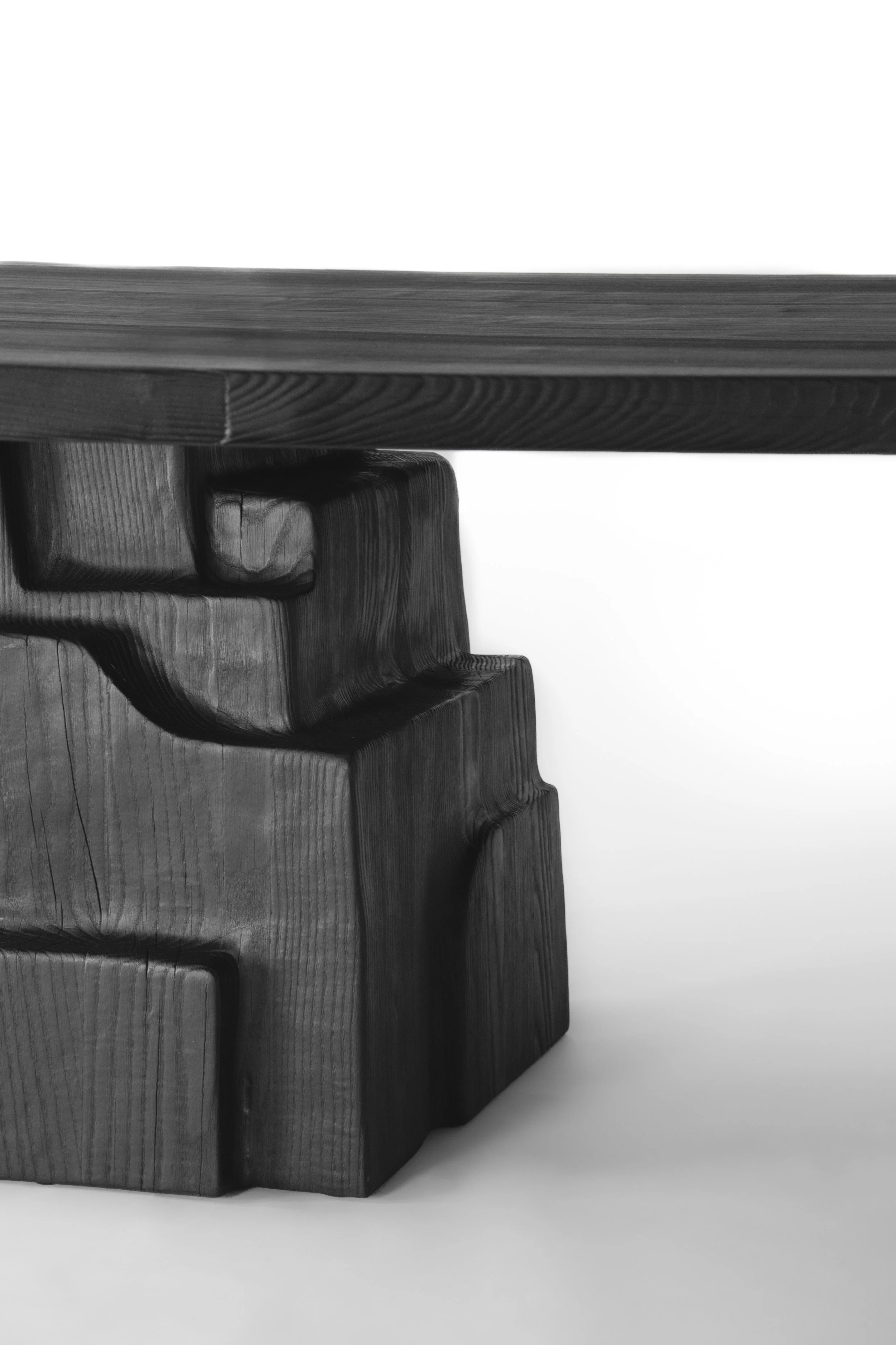 Close-up of a wooden table leg with a carved design against a white background, black and white photo.