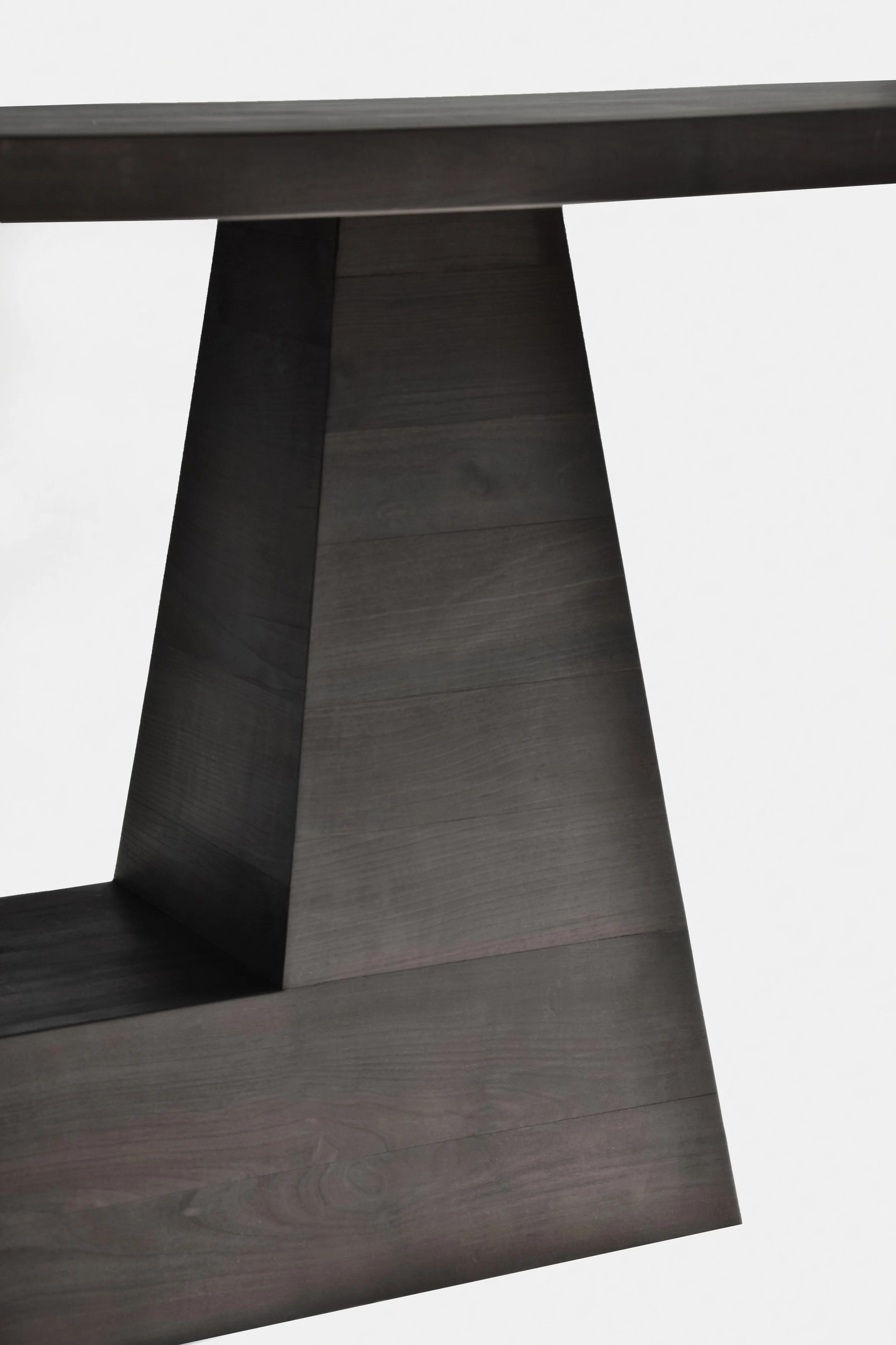 Close-up of a dark wooden tabletop with a geometric base, against a plain white background.