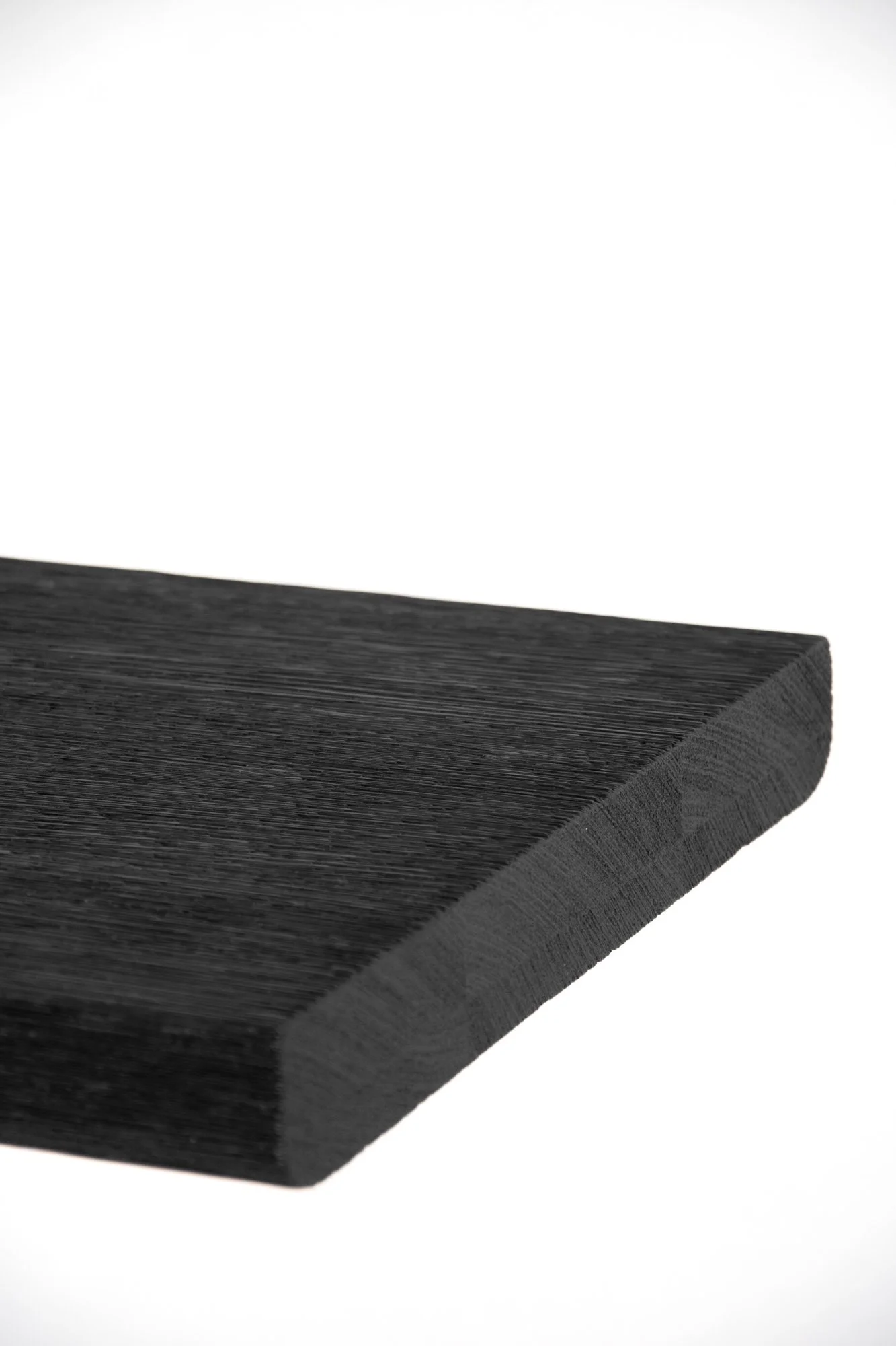 Close-up of a black triangular wooden block with visible wood grain, set against a plain white background.