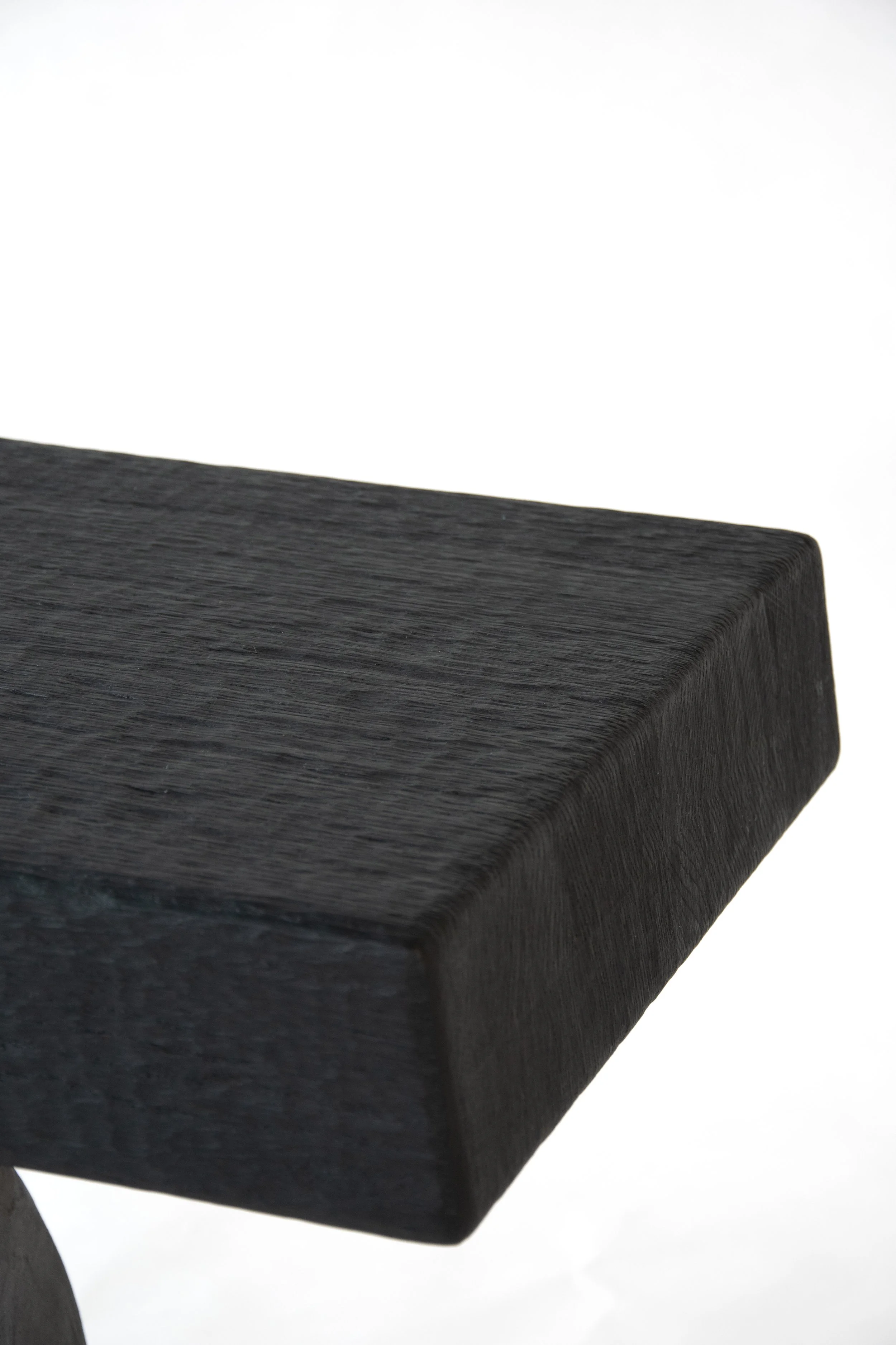 Close-up of a dark, textured wooden surface, likely a piece of furniture or a shelf, with a plain white background.