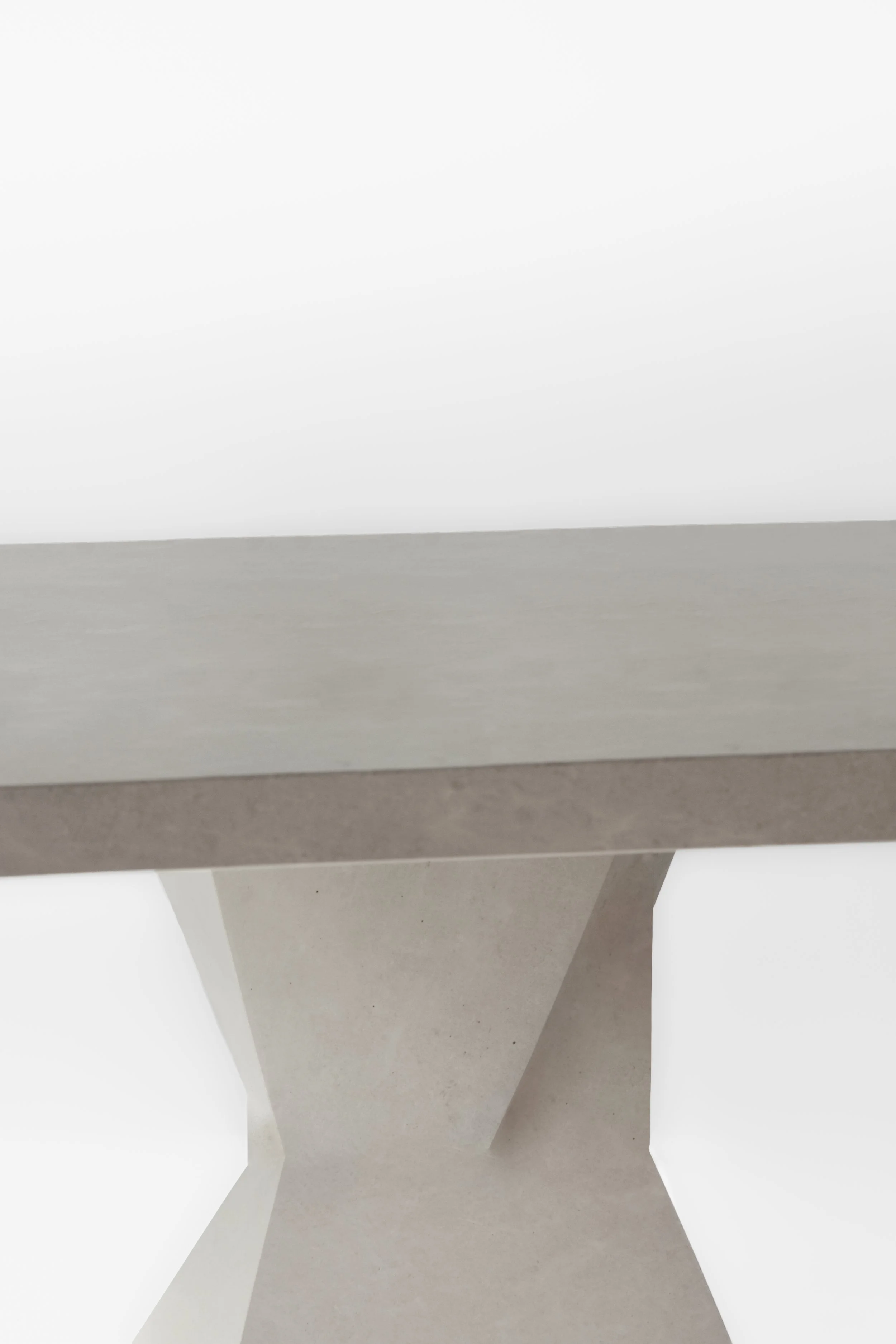 Close-up of a modern minimalistic white stone table leg and tabletop against a plain white background.