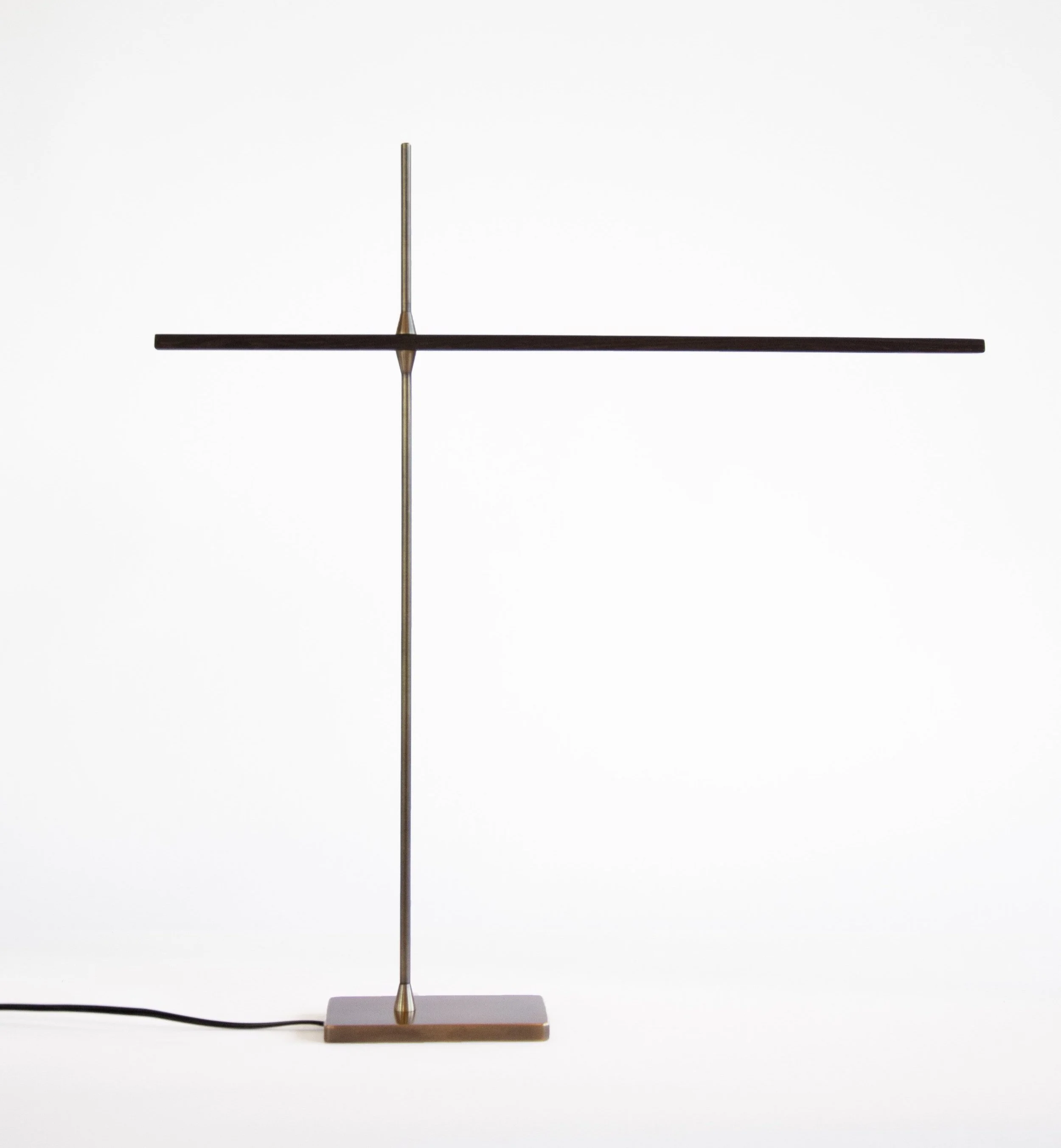 A minimalist modern lamp with a tall, slender vertical pole, a horizontal black arm, and a small rectangular base on a plain white background.