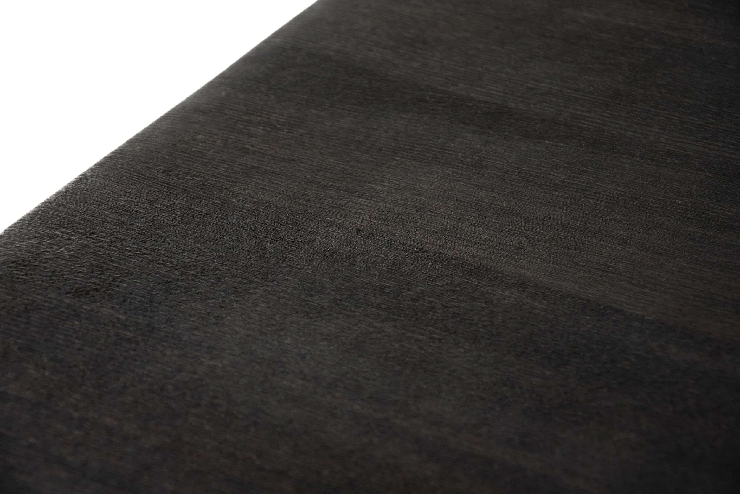 Close-up photo of a dark wooden surface with a fine, textured grain pattern.