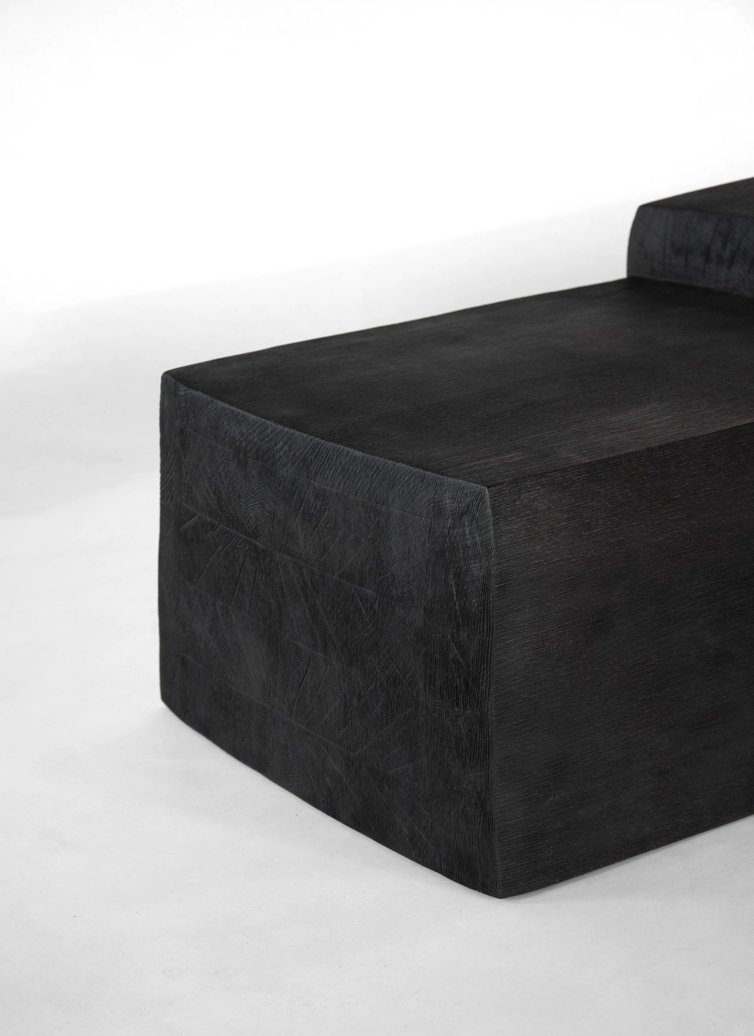 Close-up of a black upholstered bench with wood grain texture on a plain white background.