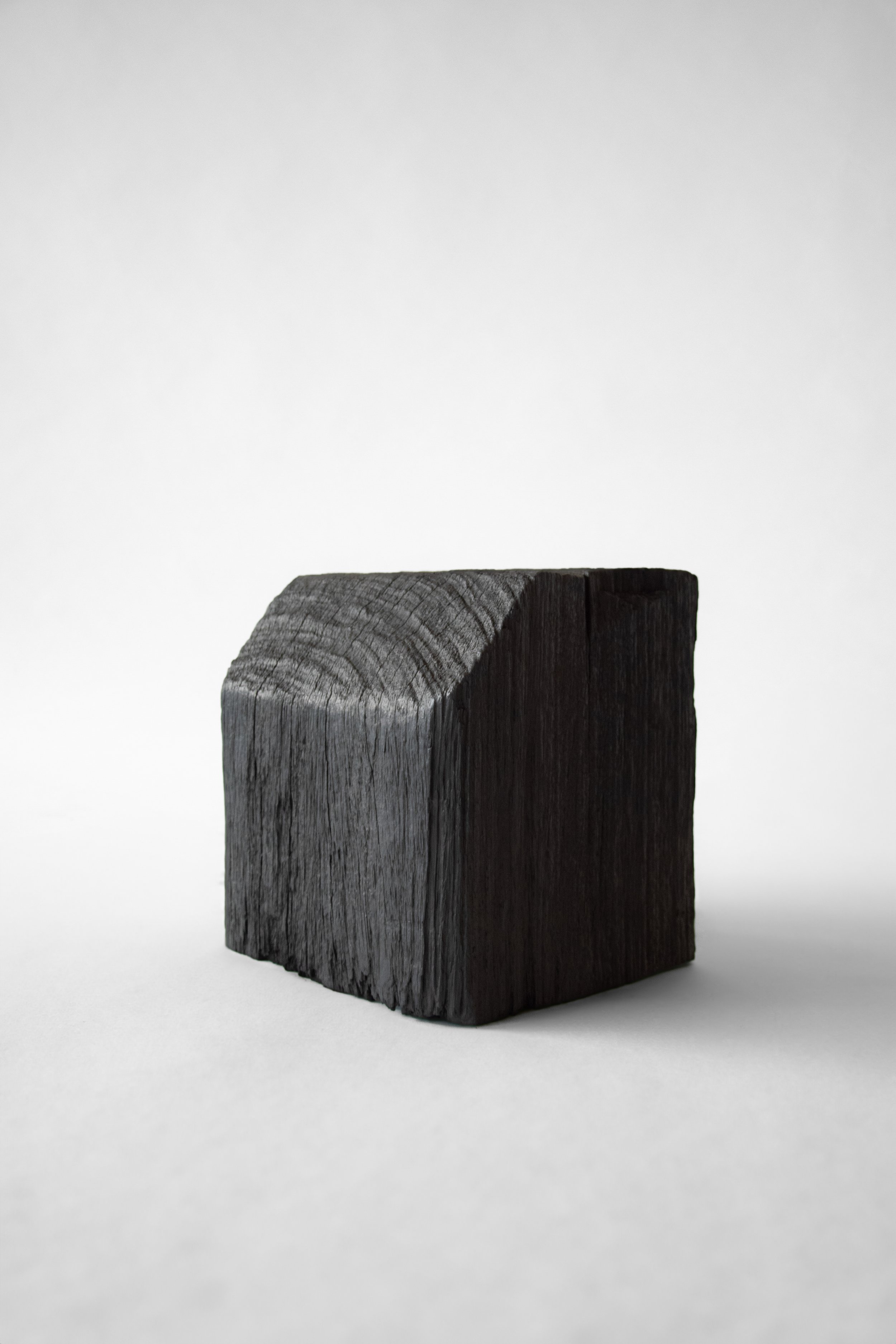 A small, dark, wooden block with a sloped top against a plain white background.