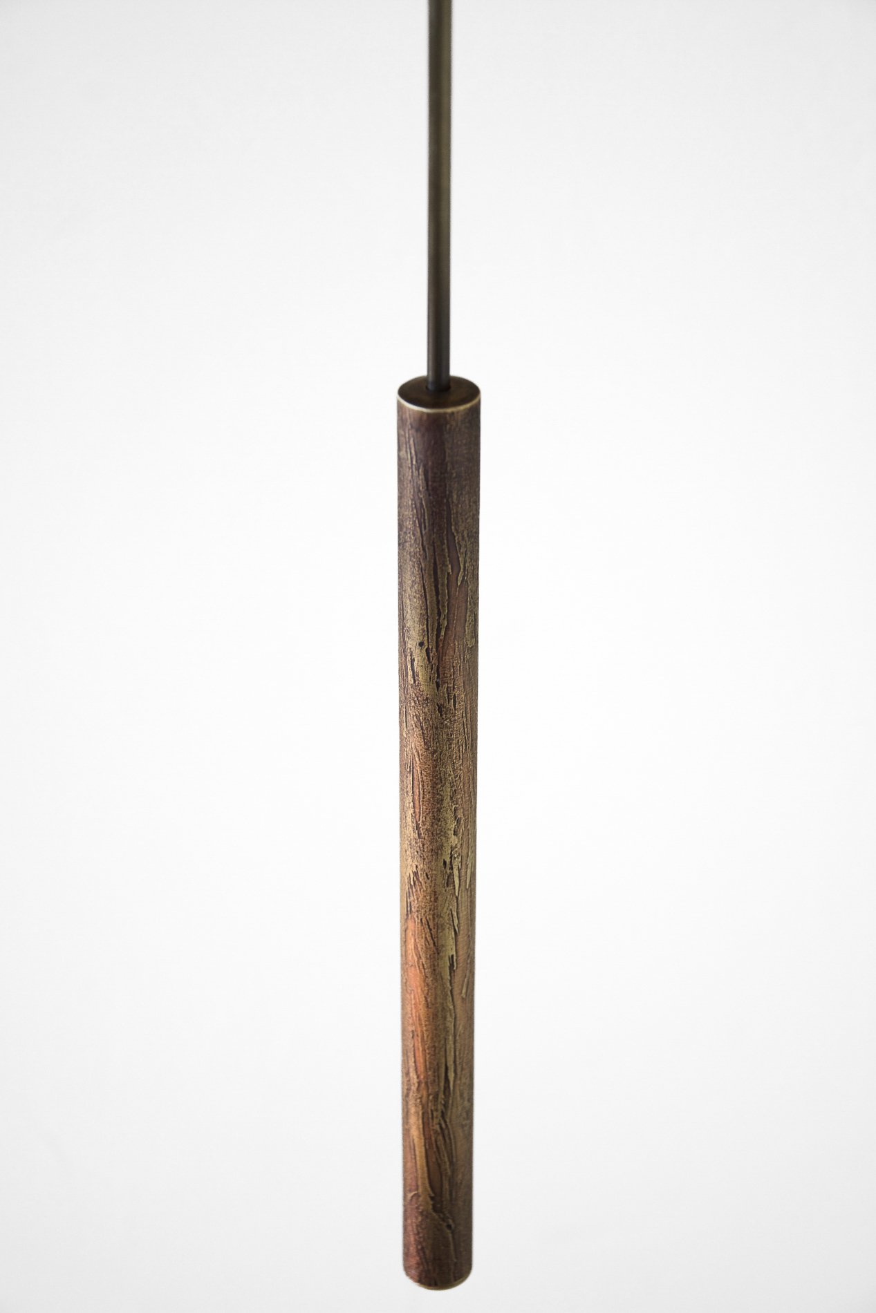 A close-up, vertical view of a pendant lamp with a brass shaft against a plain white background.