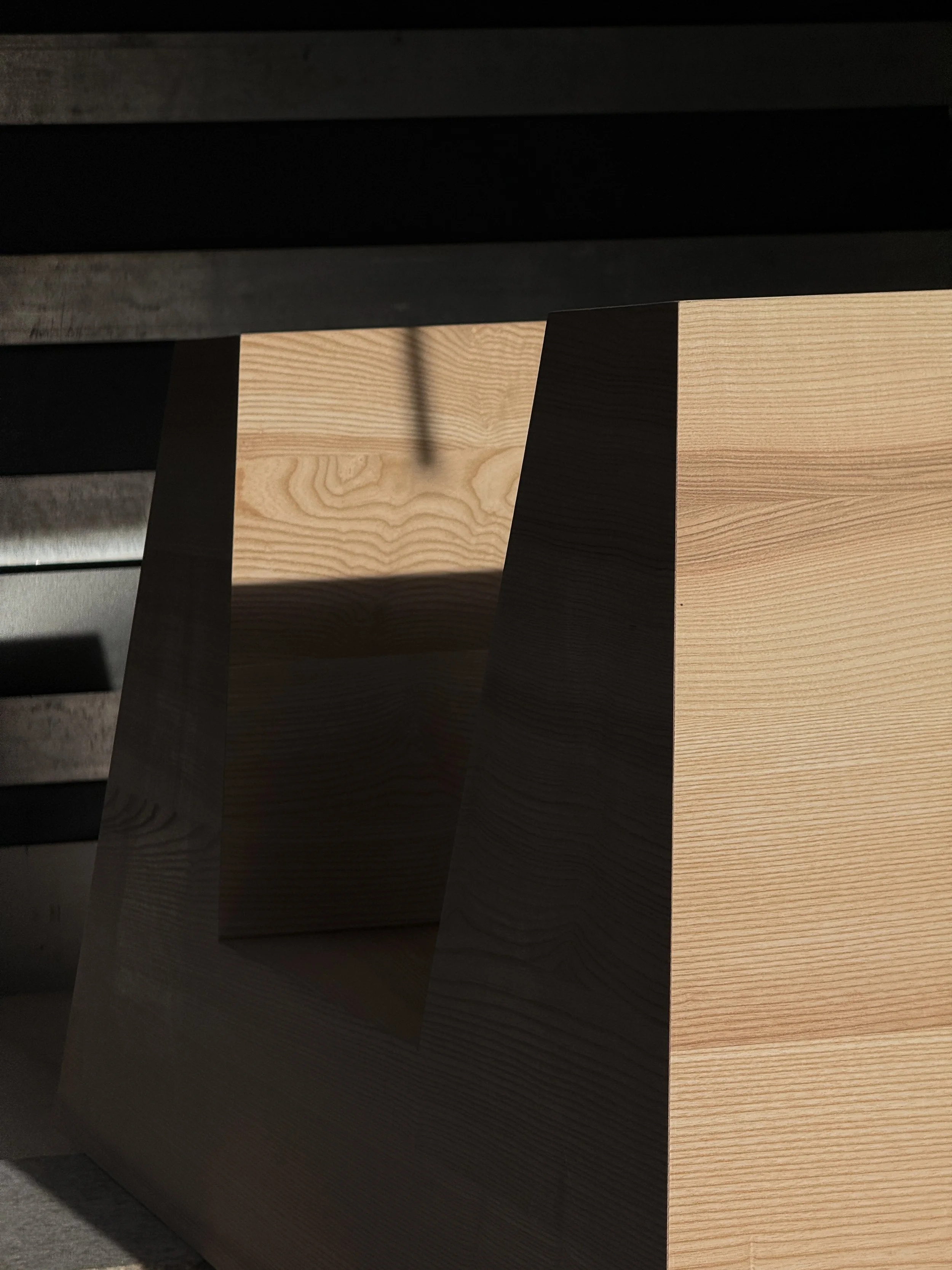 Close-up of wooden furniture with a black surface on top, showing light and shadow play on the wood grain.