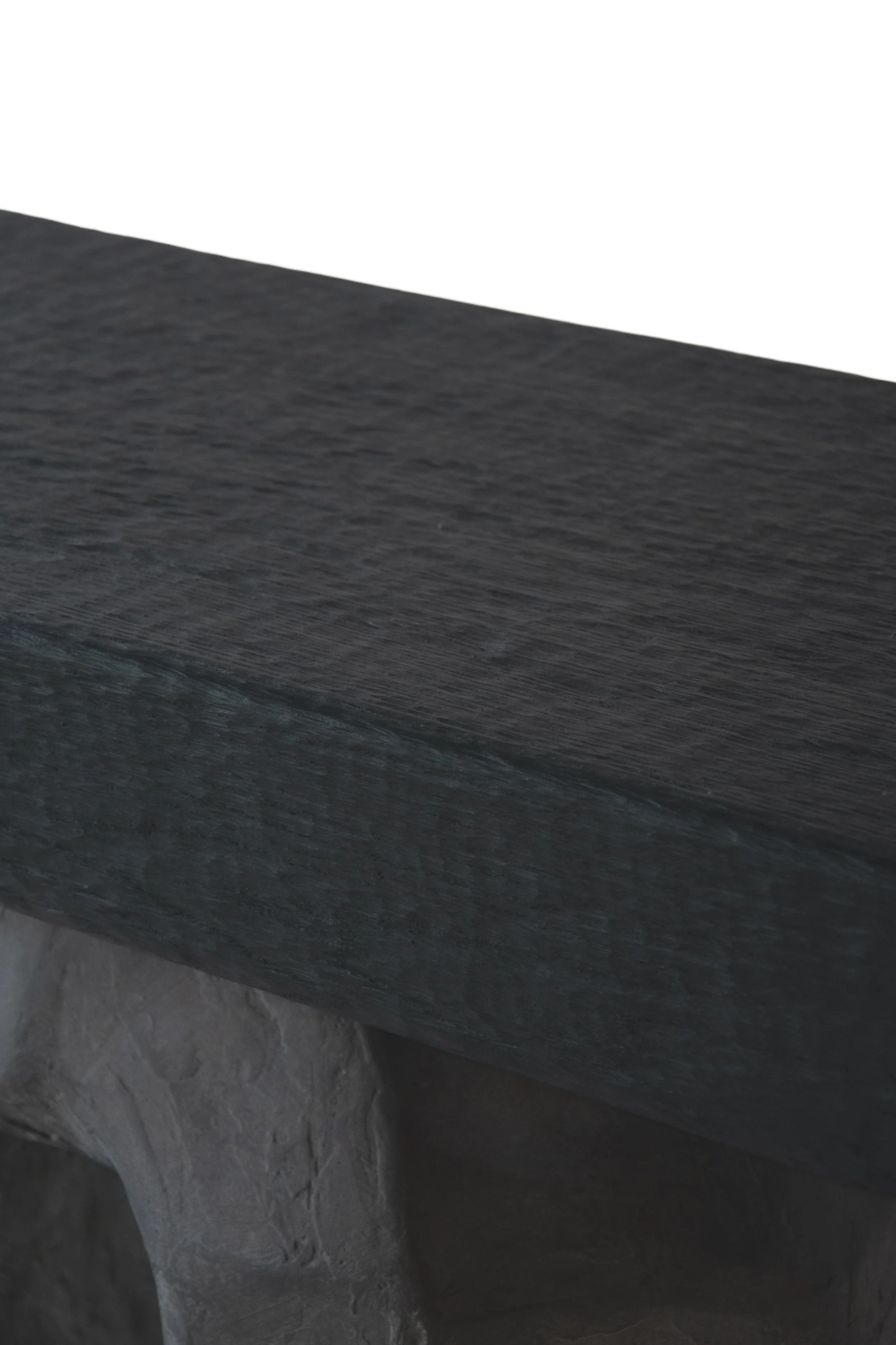 Close-up of a dark-colored wooden surface with a stone or concrete base beneath it.