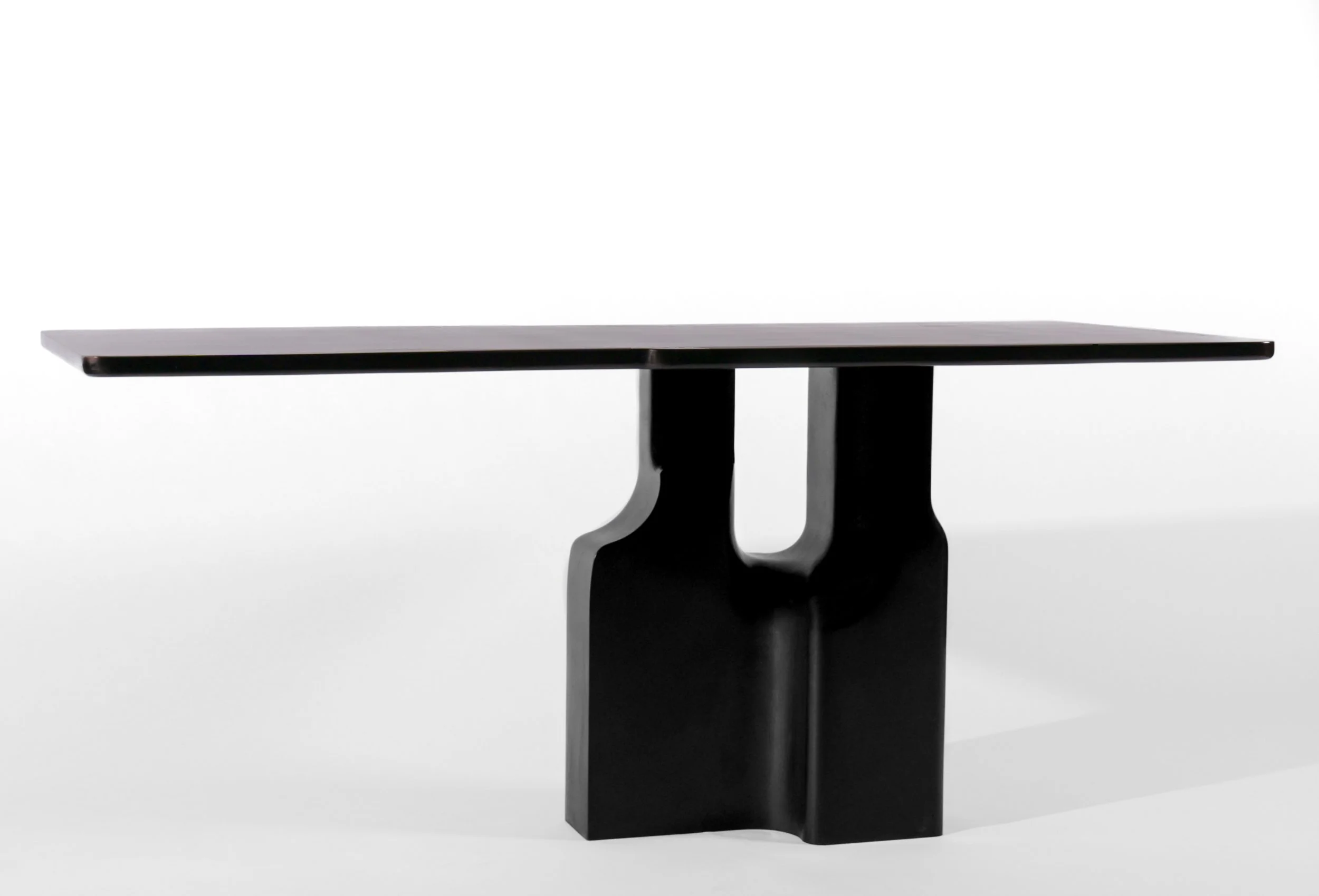 Modern black table with a sculptural base and a flat rectangular top, set against a plain white background.