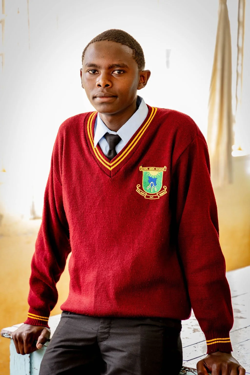 Young man in school uniform with burgundy sweater and badge