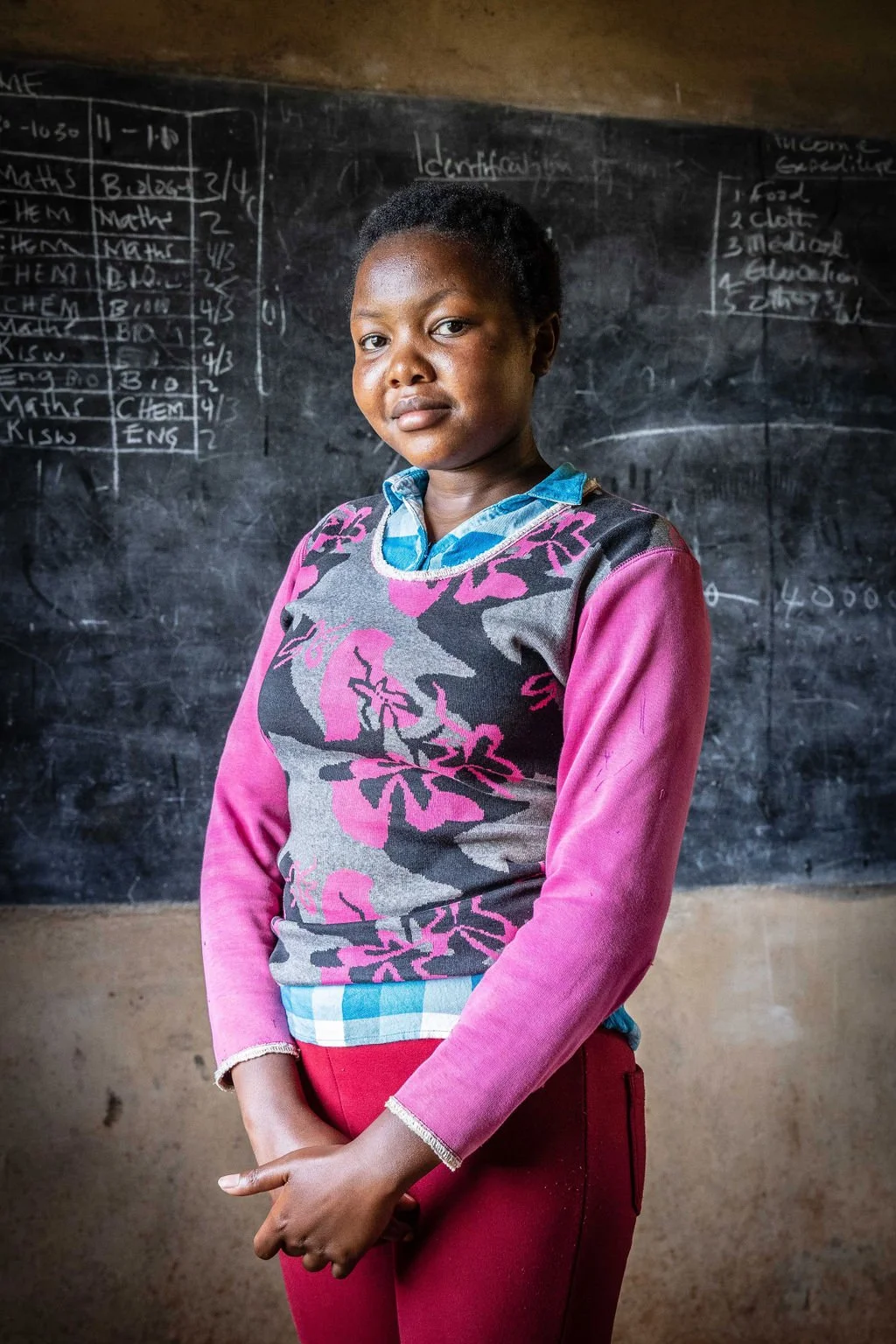 Person standing in front of a chalkboard with writing and a schedule.