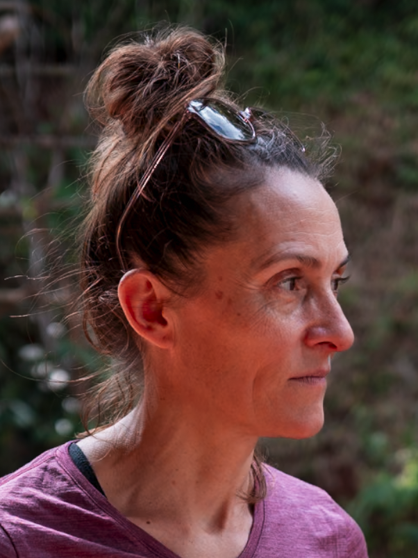 Smiling manwearing glasses outdoors with a building in the background.