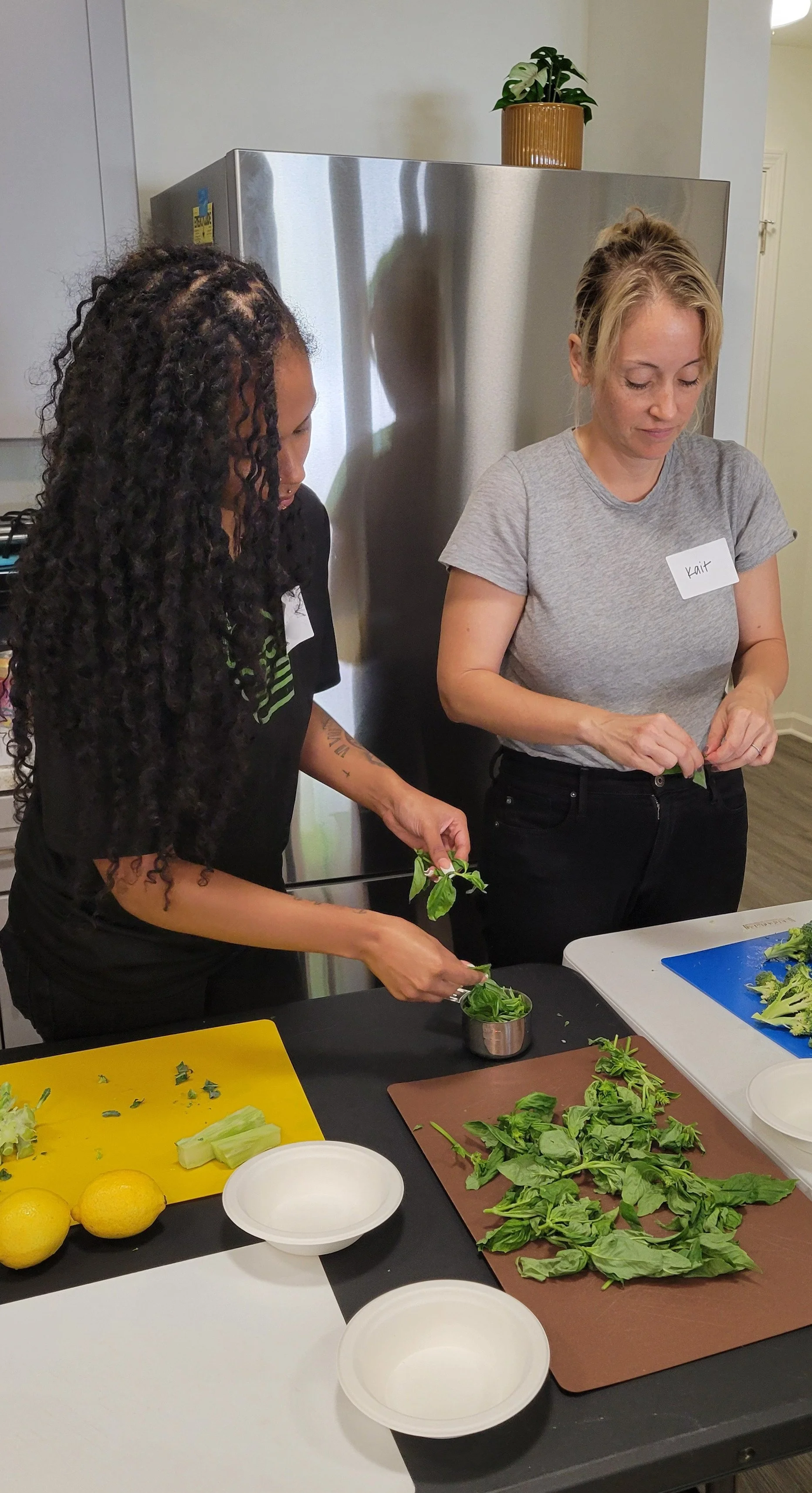 Kitchen Compass client preparing basil for pesto with Kait from Burkett Farm.