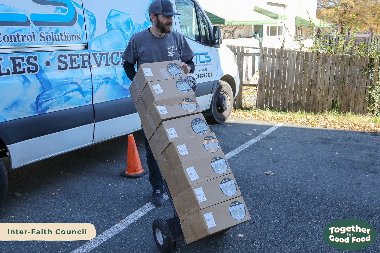 Equiti Foods employee moving eight boxes of Good Bowls on a dolly outside of Inter-Faith Council. 