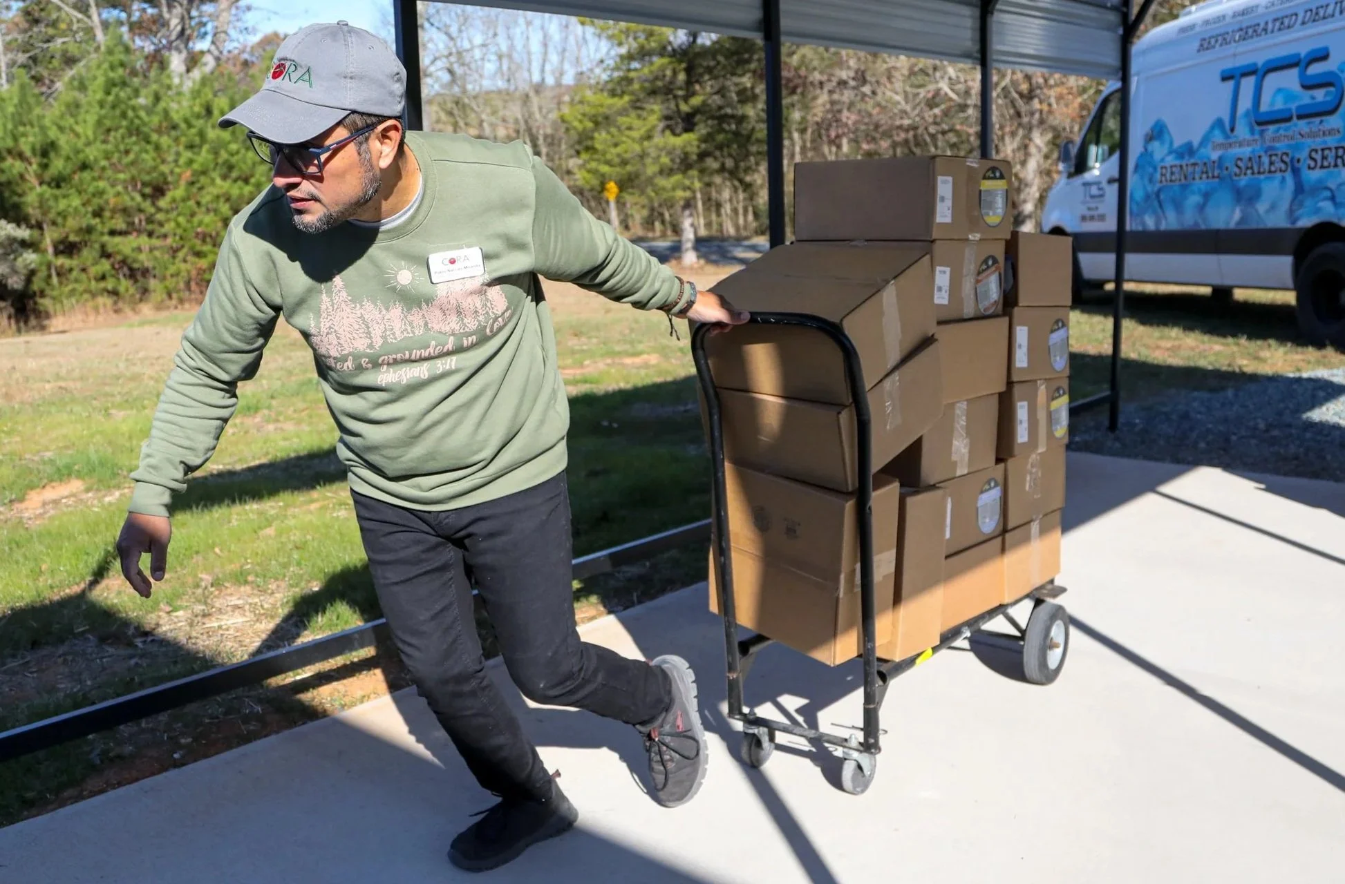 Pablo of CORA Food Pantry pulling a cart with many boxes of Good Bowls.