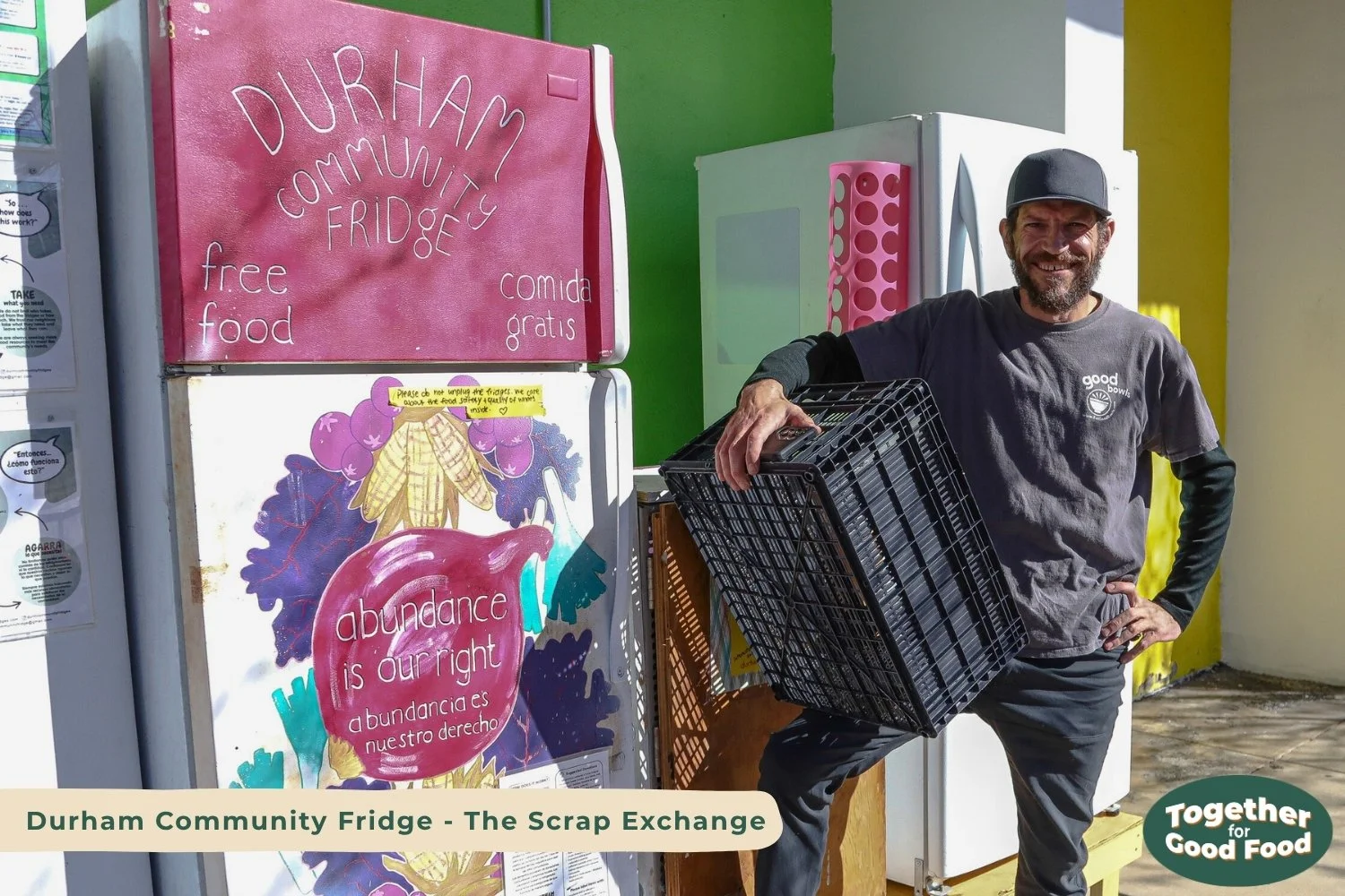 Equiti Foods employee standing in front of the pink Durham Community Fridge outside The Scrap Exchange. He is holding an empty crate after filling the freezer with Good Bowls. The fridge reads, "abundance is our right." 