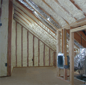 Construction site showing exposed wooden framing, insulation, and ductwork in an unfinished attic or ceiling space.