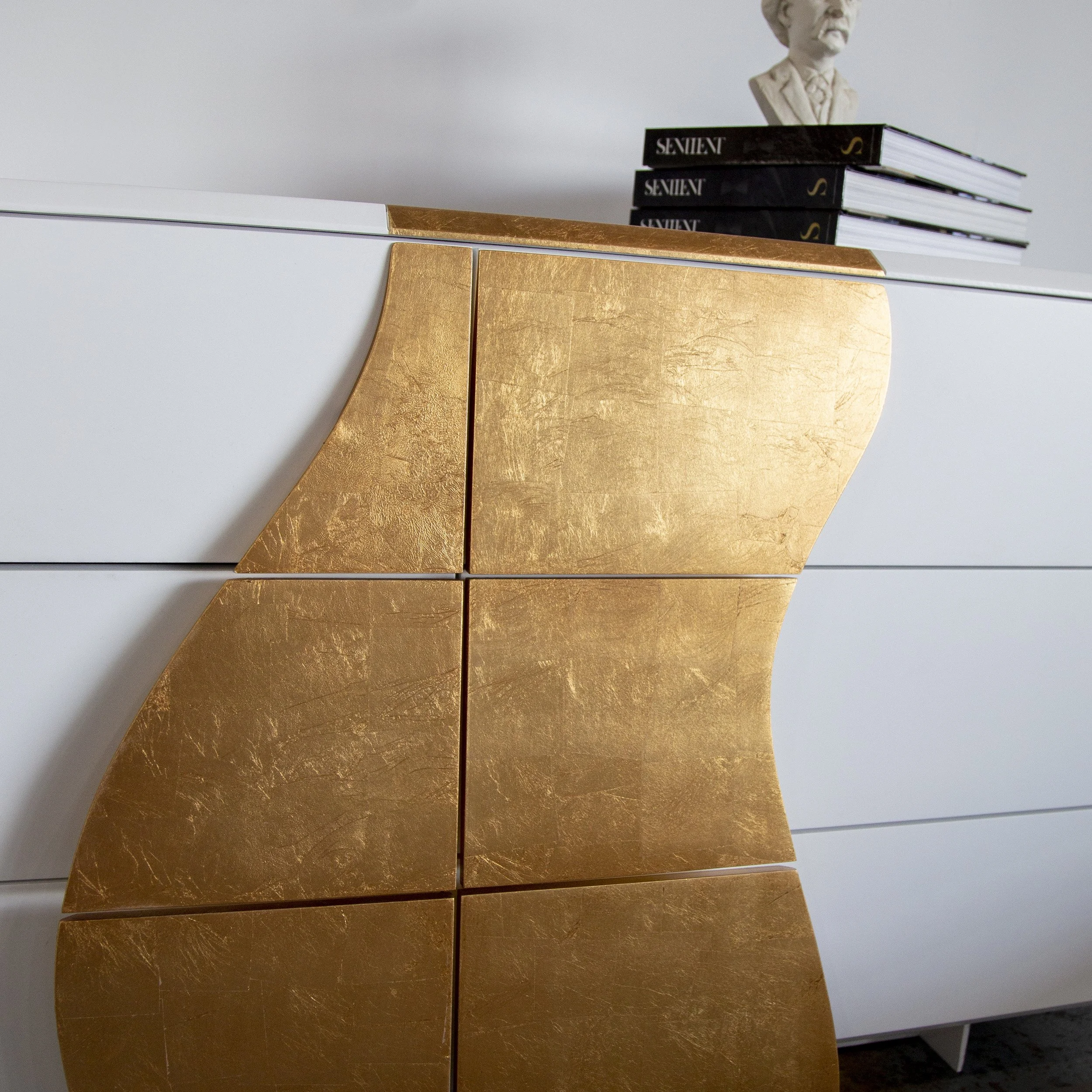 Gold leaf detail on Melodious Dresser with SENTIENT books and a bust above