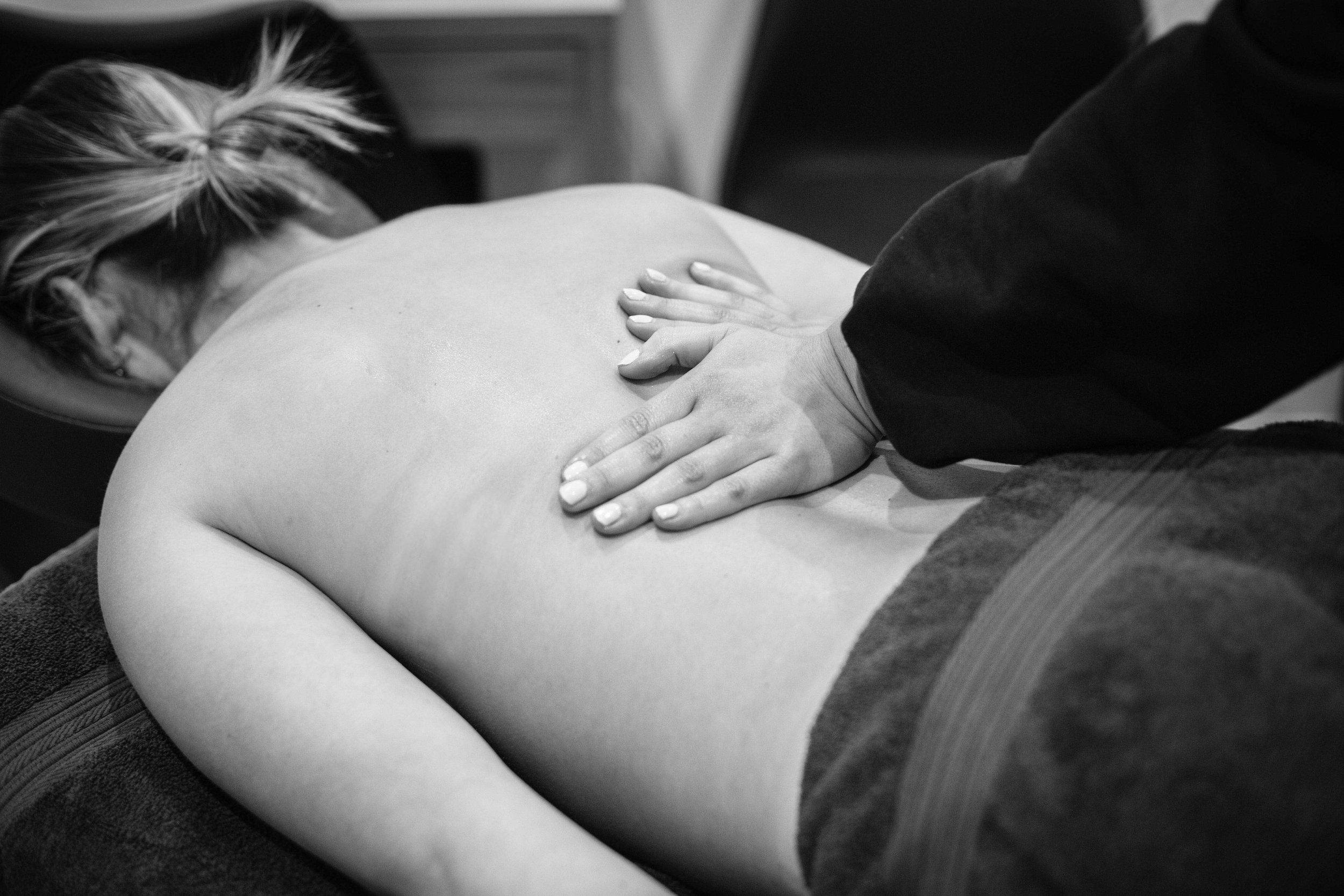 A person receives a back massage from a massage therapist in a spa or massage setting.