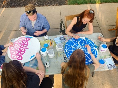 people painting circular geometric designs outdoors