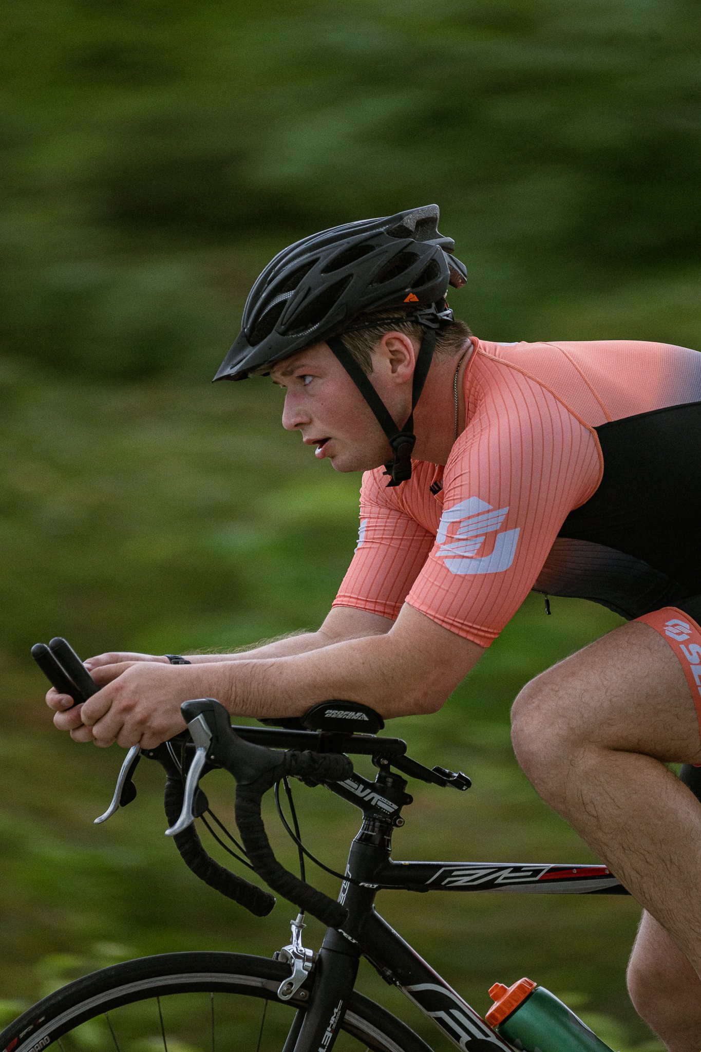 Young man in a trisuit cycling with a blurred background