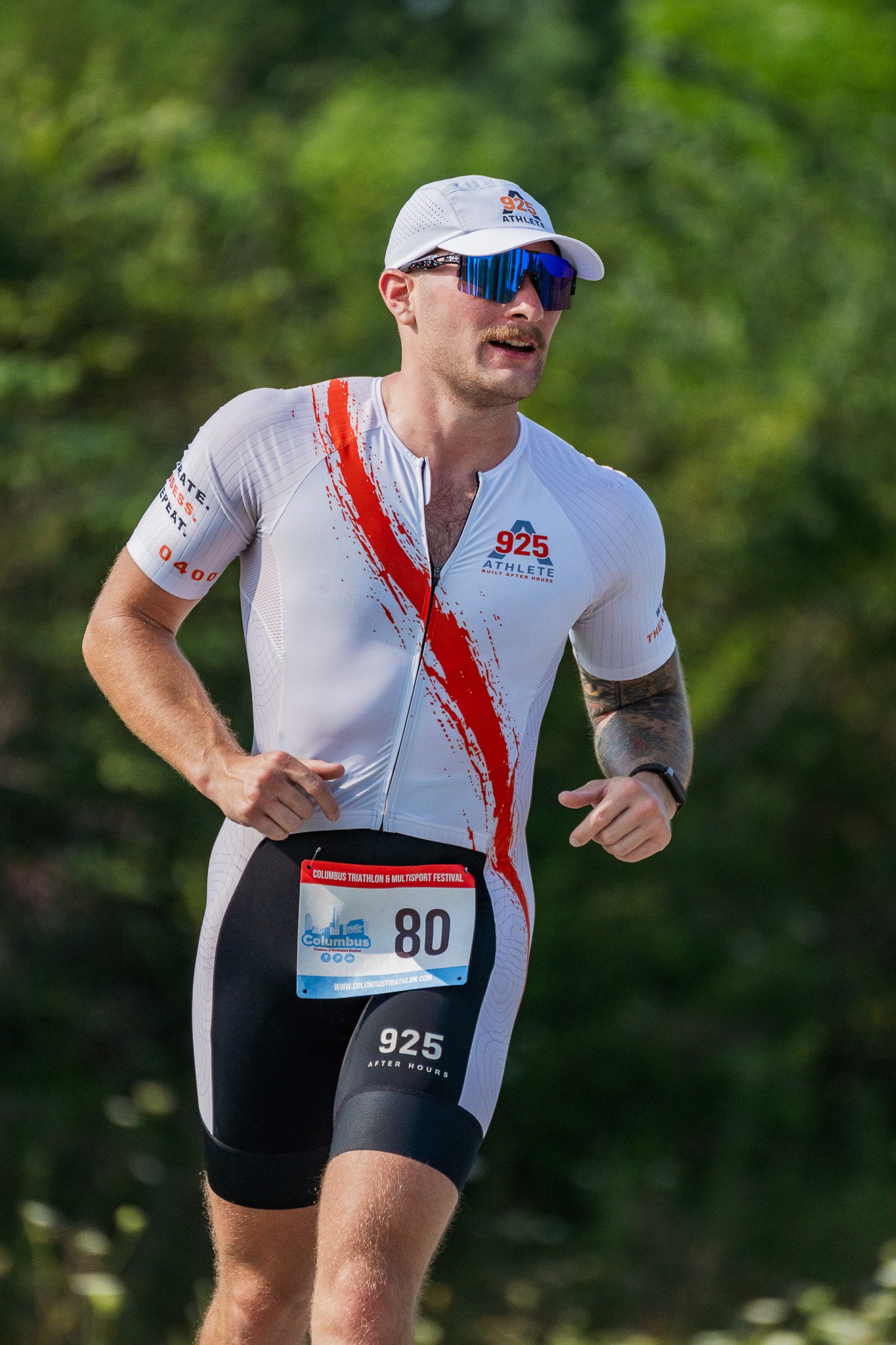 Young man in all white runs in a triathlon