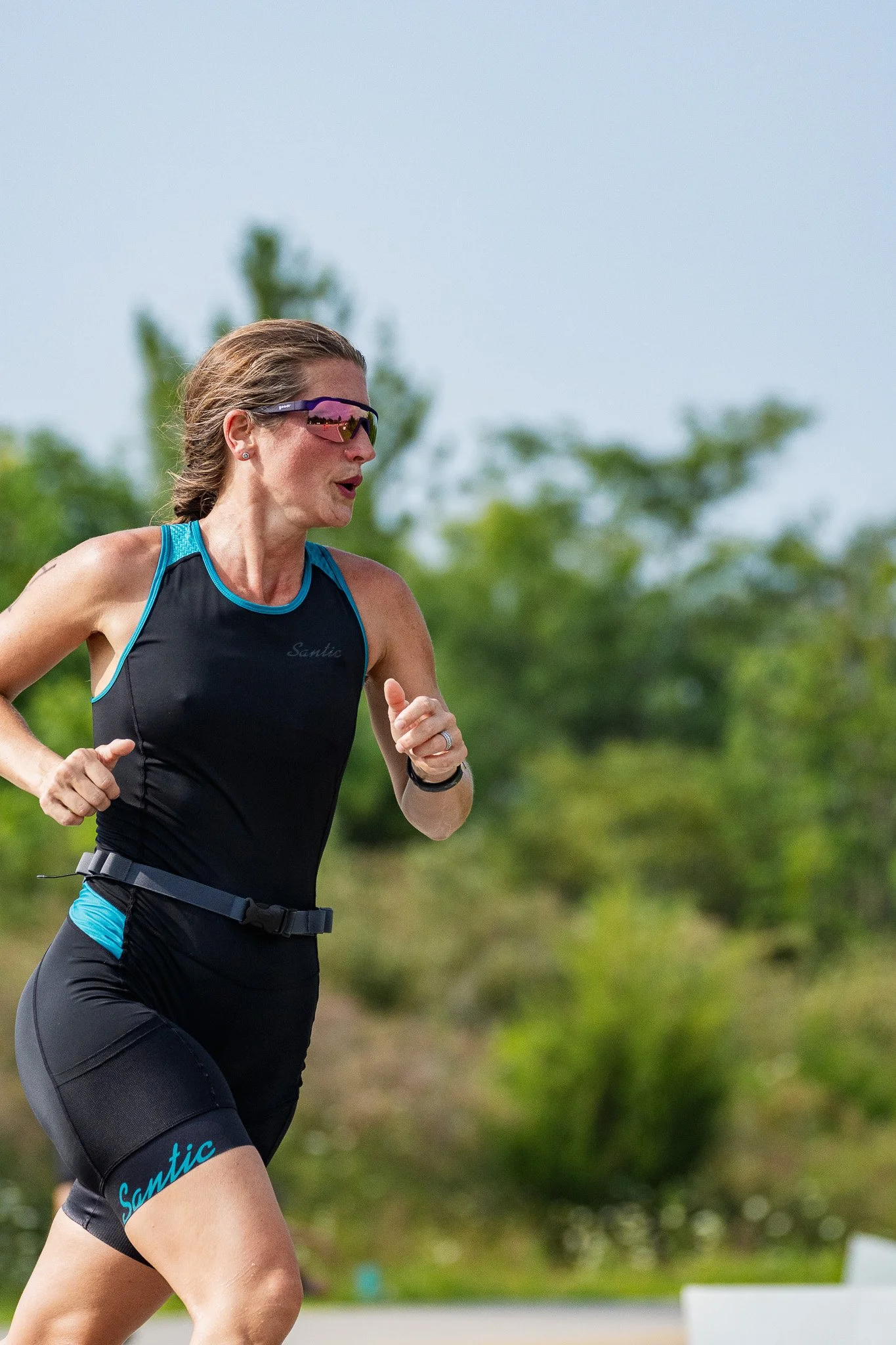 A woman in a black trisuit running the final leg of a triathlon