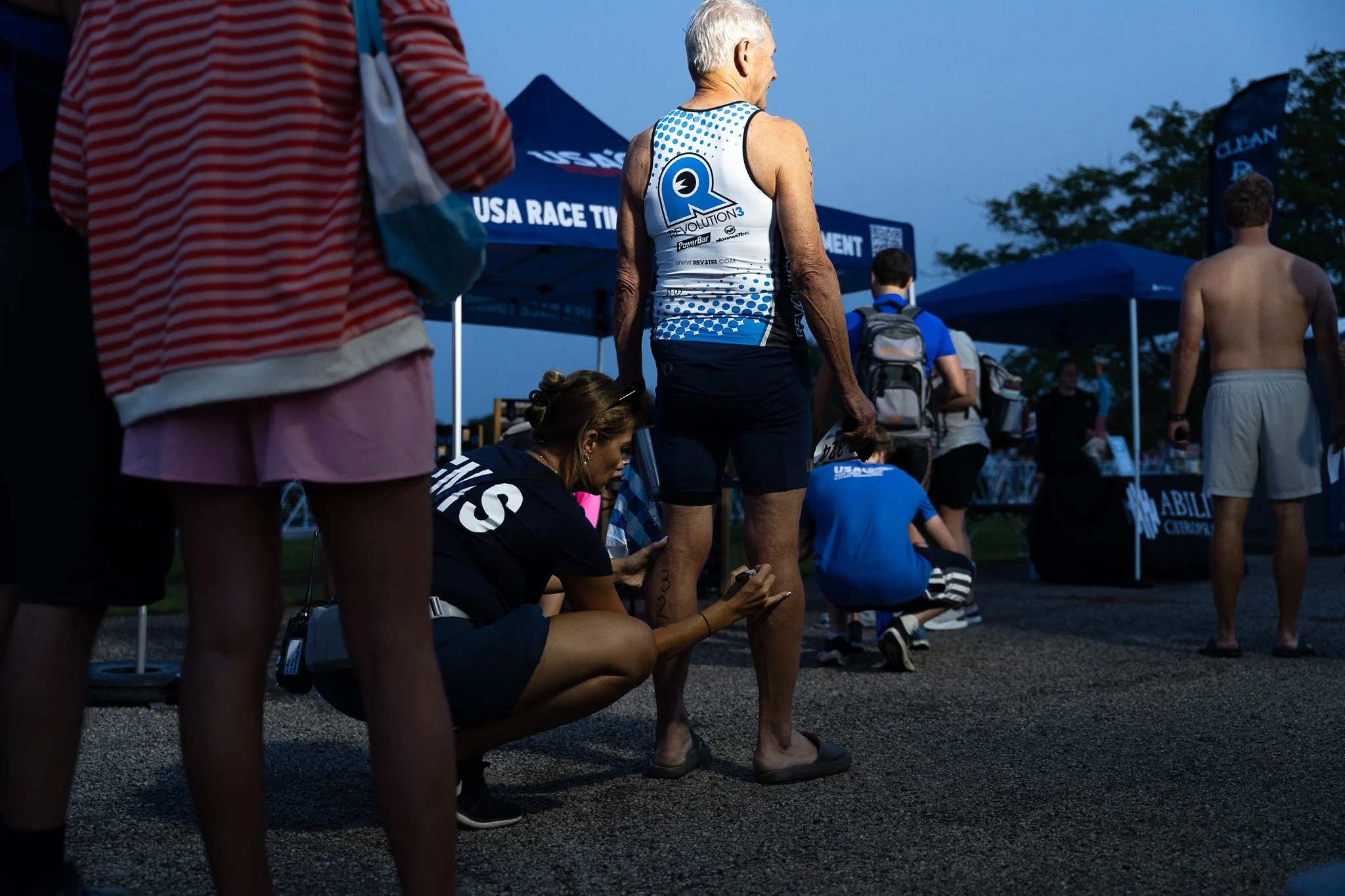 EMS worker writes a number on a runner's leg before a race