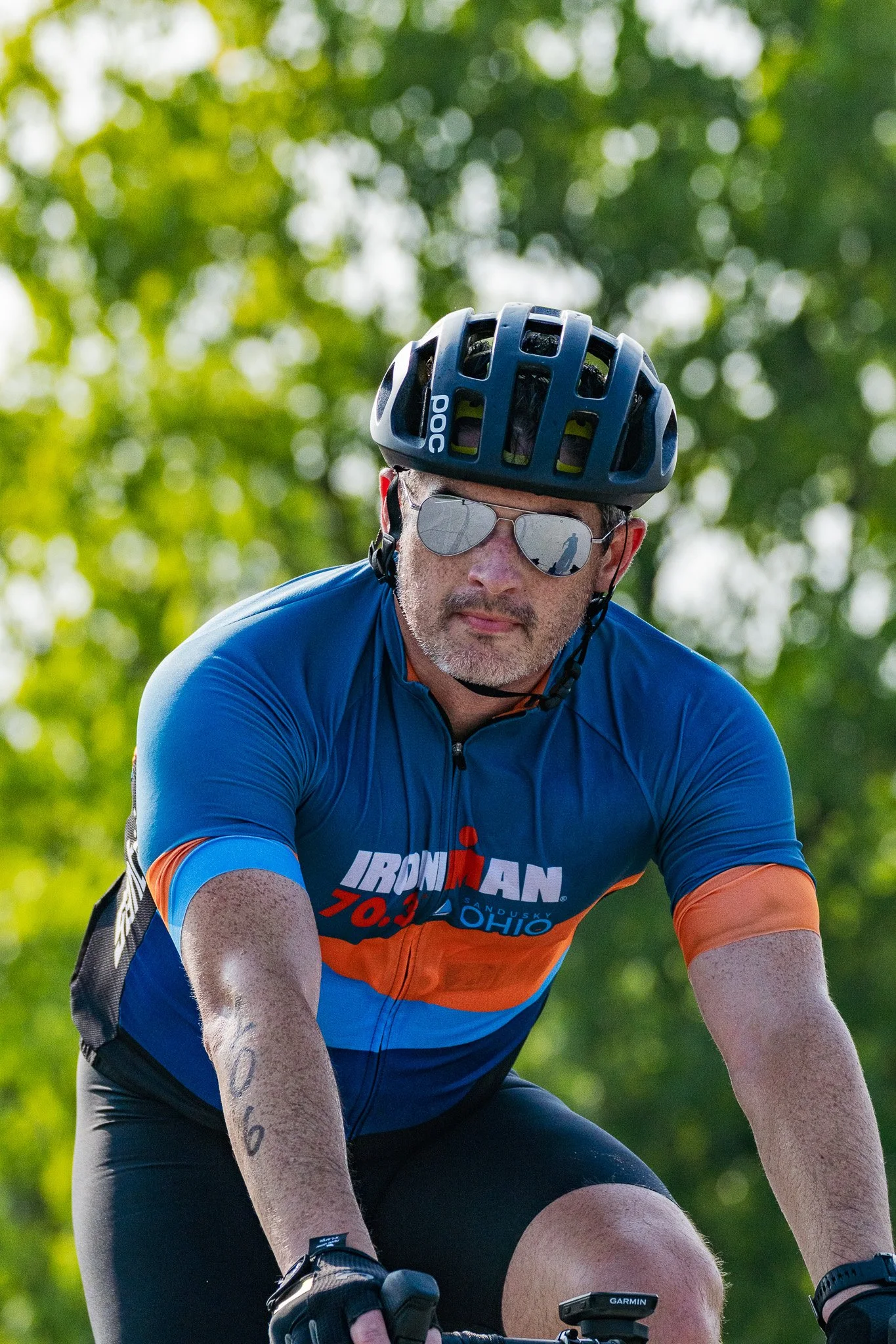 Man in an Ironman 70.3 shirt cycles in a triathlon