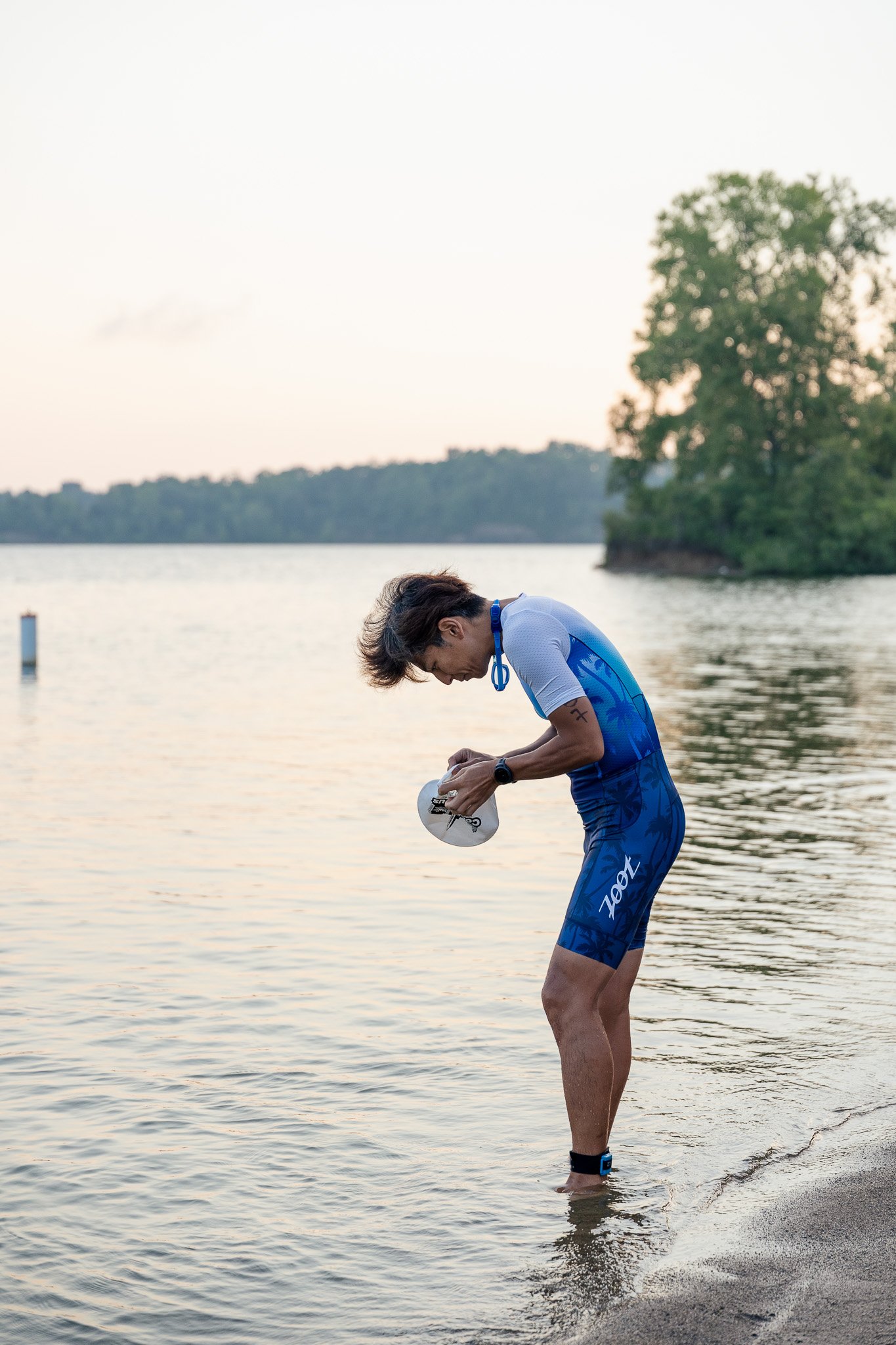 Swimmer putting cap on during sunrise before a triathlon