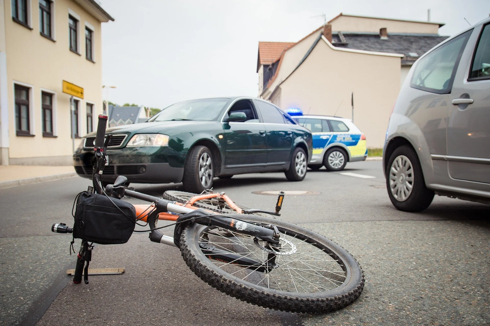 Bicycle lying on the road beside a car and police vehicle after a bicycle accident